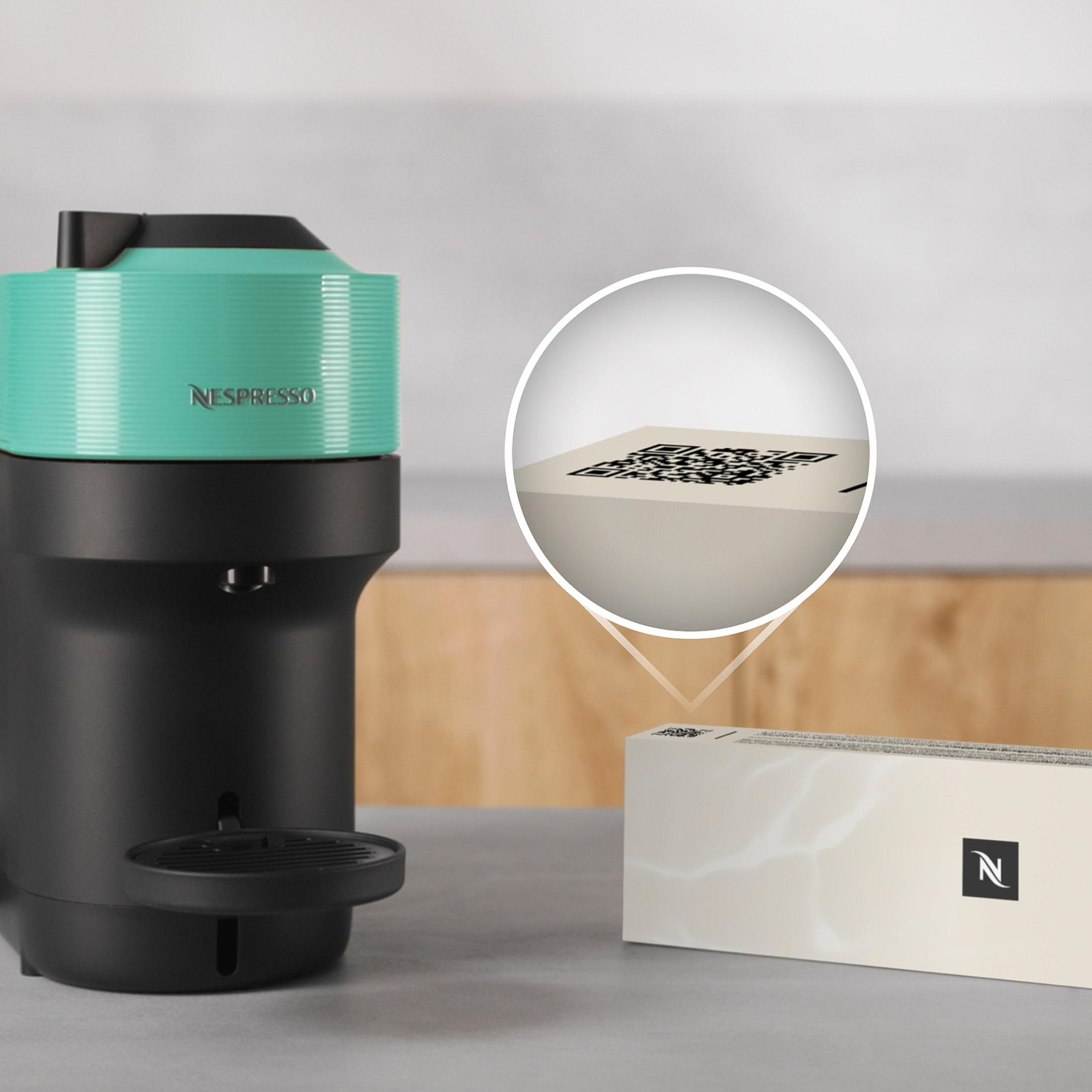 Una macchina Nespresso accanto a una confezione con codice QR.