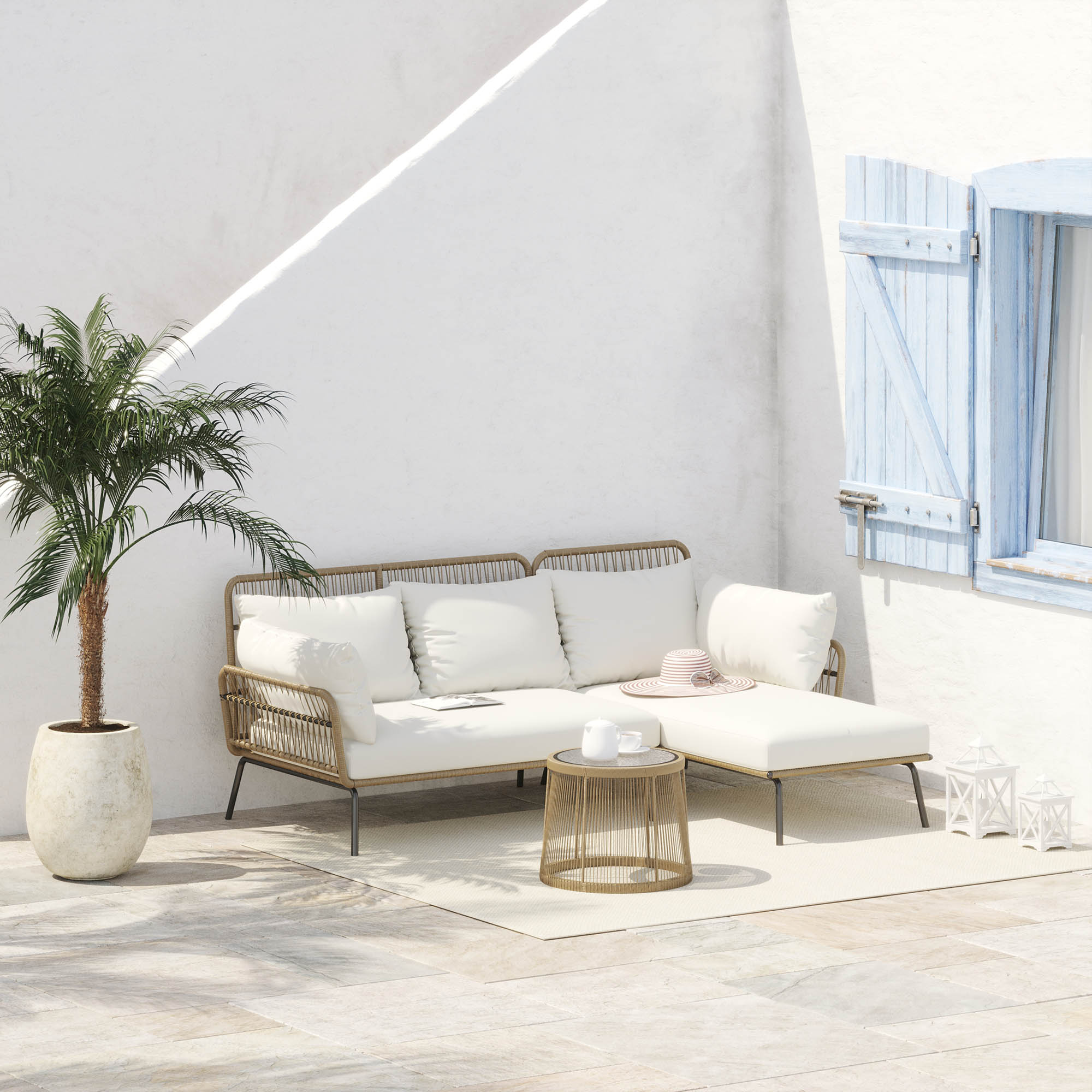 Un divano bianco con finiture in rattan beige siede su un tappeto chiaro contro un muro bianco.