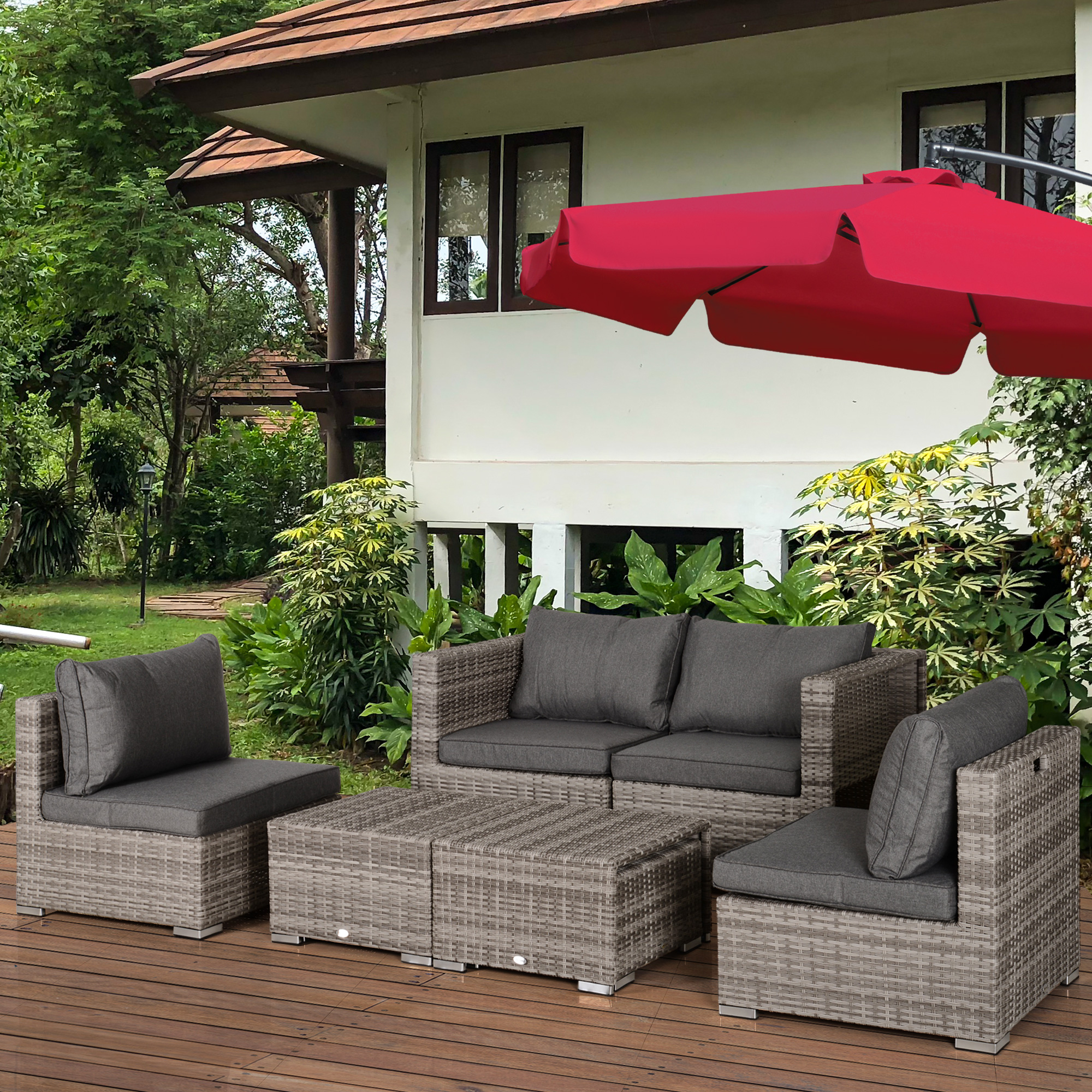 Mobili da giardino in rattan grigio con cuscini sotto un ombrellone rosso.