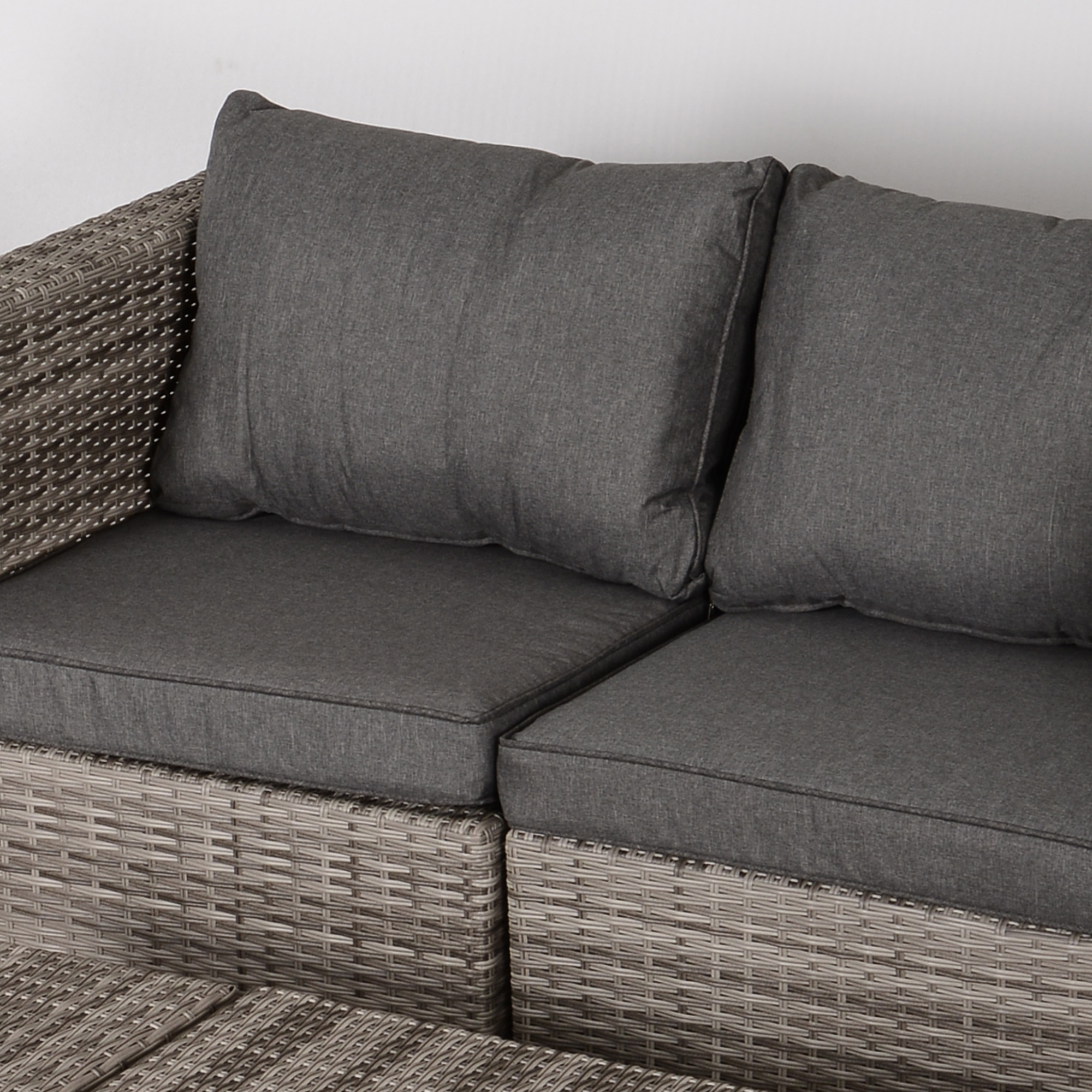 Cuscini grigi su un divano in rattan con sfondo bianco.