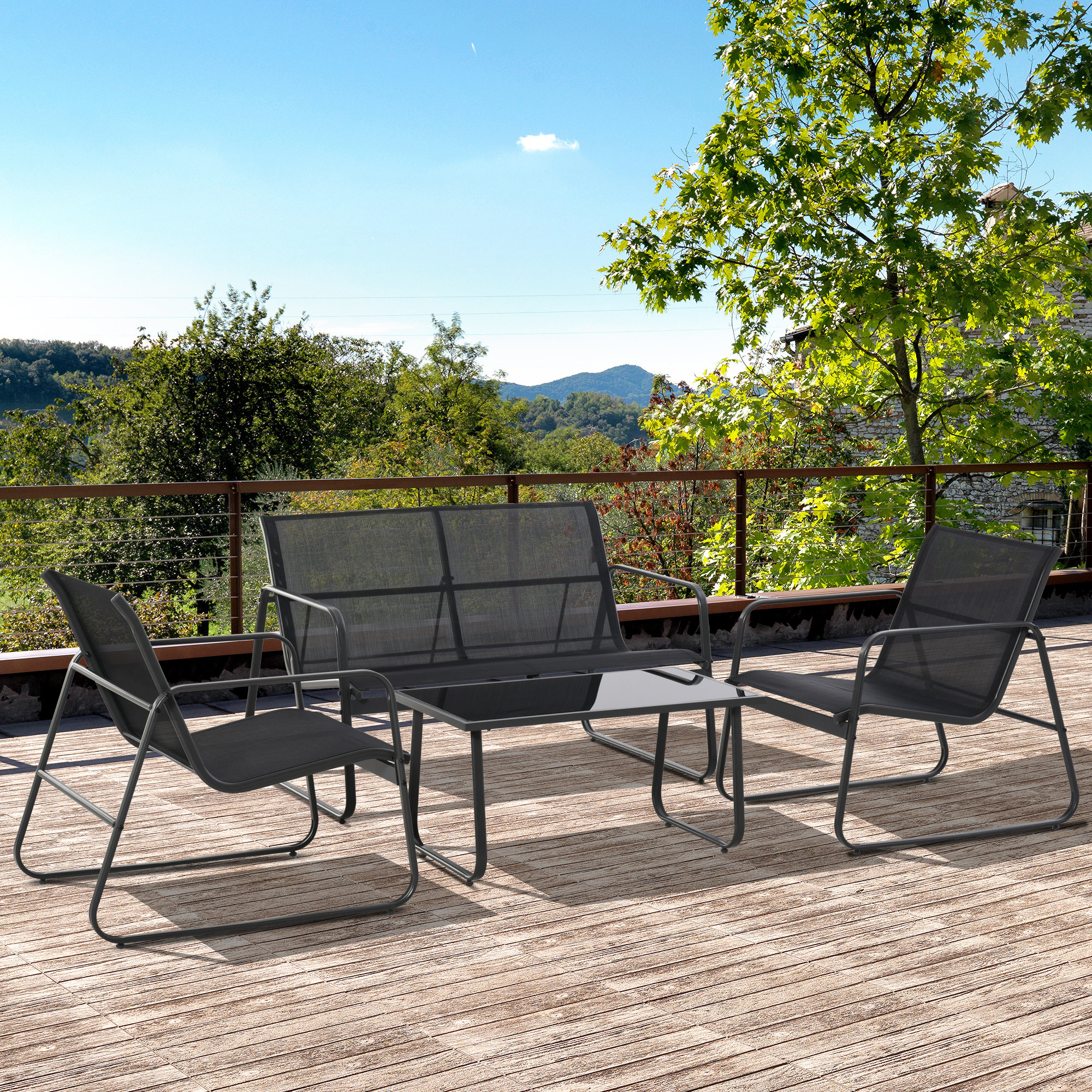 Set di mobili da giardino scuri su un ponte di legno, con vista su alberi e montagne.
