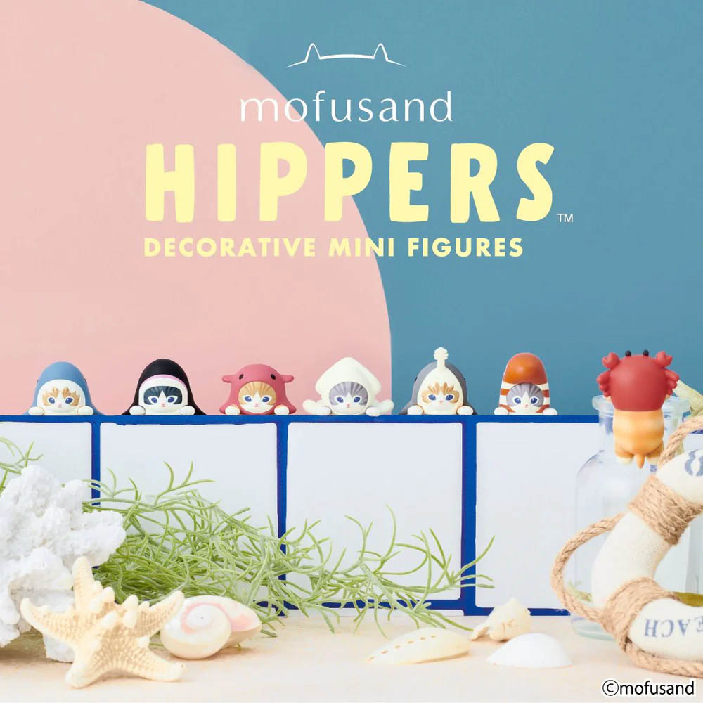 Mofusand dekorative Mini-Figuren von Katzen in Kostümen und eine Krabbe am Strand.