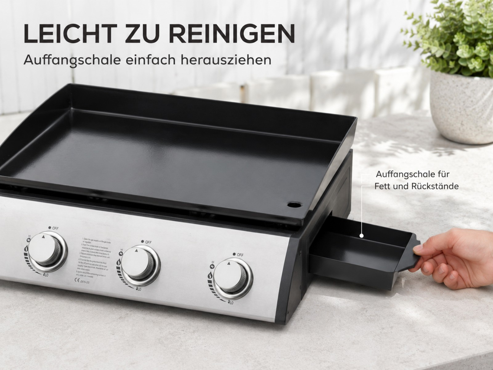 Ein silberner Grill mit schwarzer Platte und herausziehbarer Fettauffangschale.