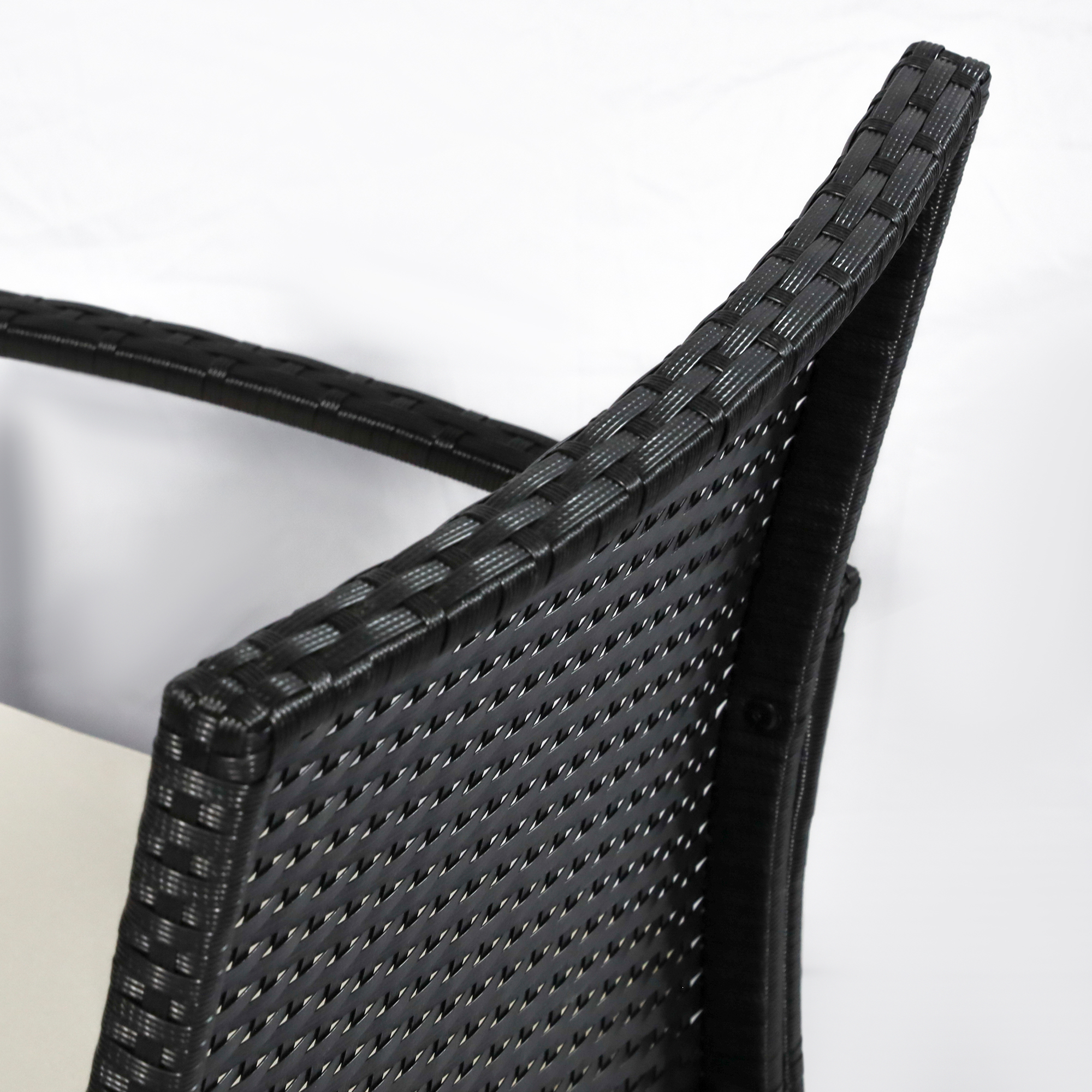 Primo piano di una sedia in rattan nero con schienale e bracciolo curvi.