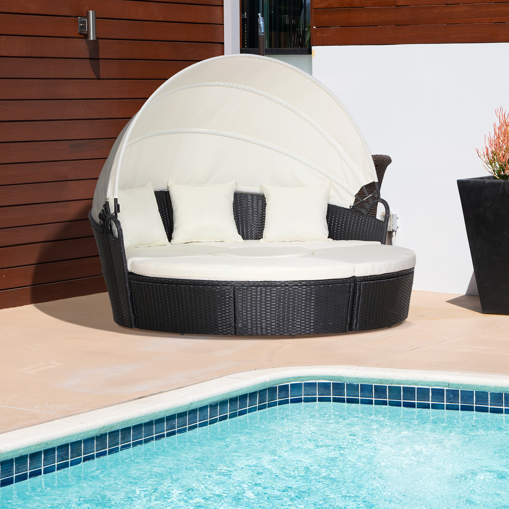 Daybed rotondo da esterno con baldacchino e cuscini color crema, vicino a piscina.