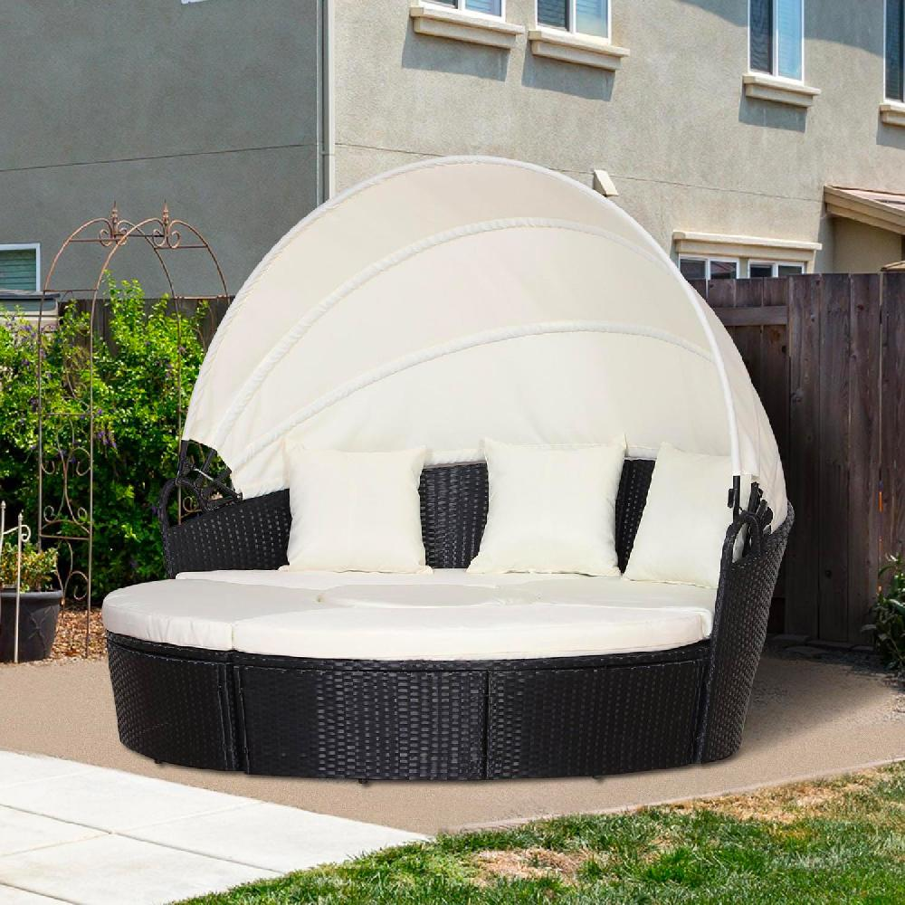Daybed rotondo in rattan nero con baldacchino bianco e cuscini in giardino.