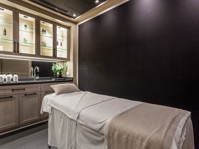 Una cama de tratamiento de spa con gabinetes y productos.