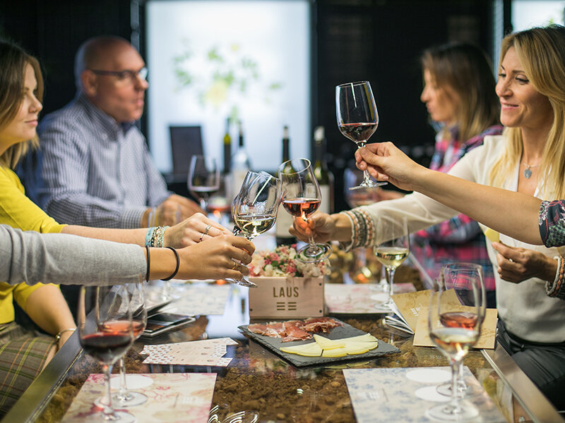 La gente brinda con vino mientras está sentada en una degustación.