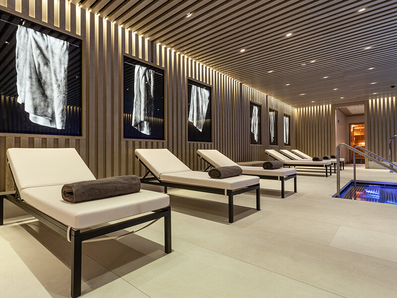 Un área de spa con tumbonas, toallas y una piscina.