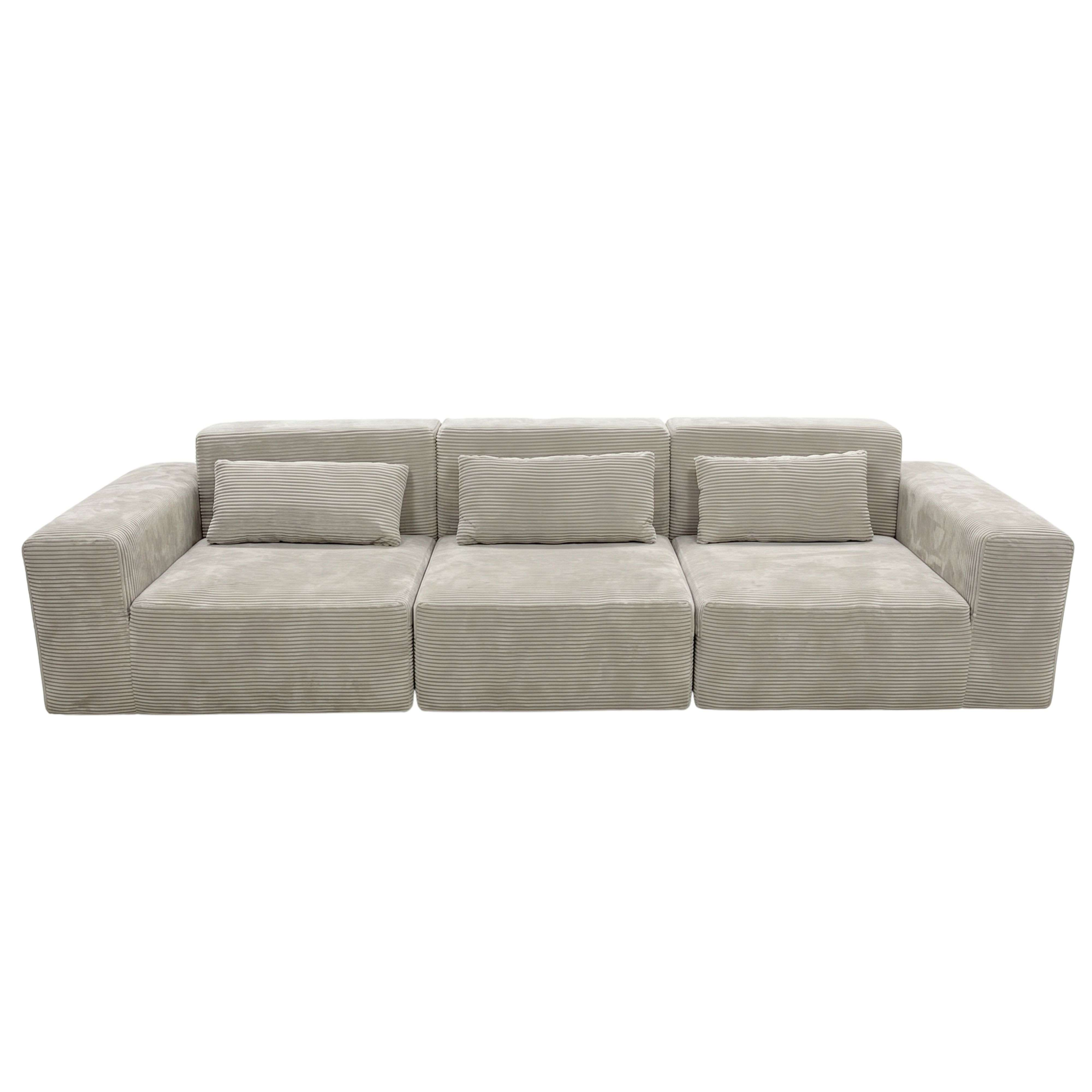 Un sofá de pana gris claro con tres secciones de asiento y tres cojines.