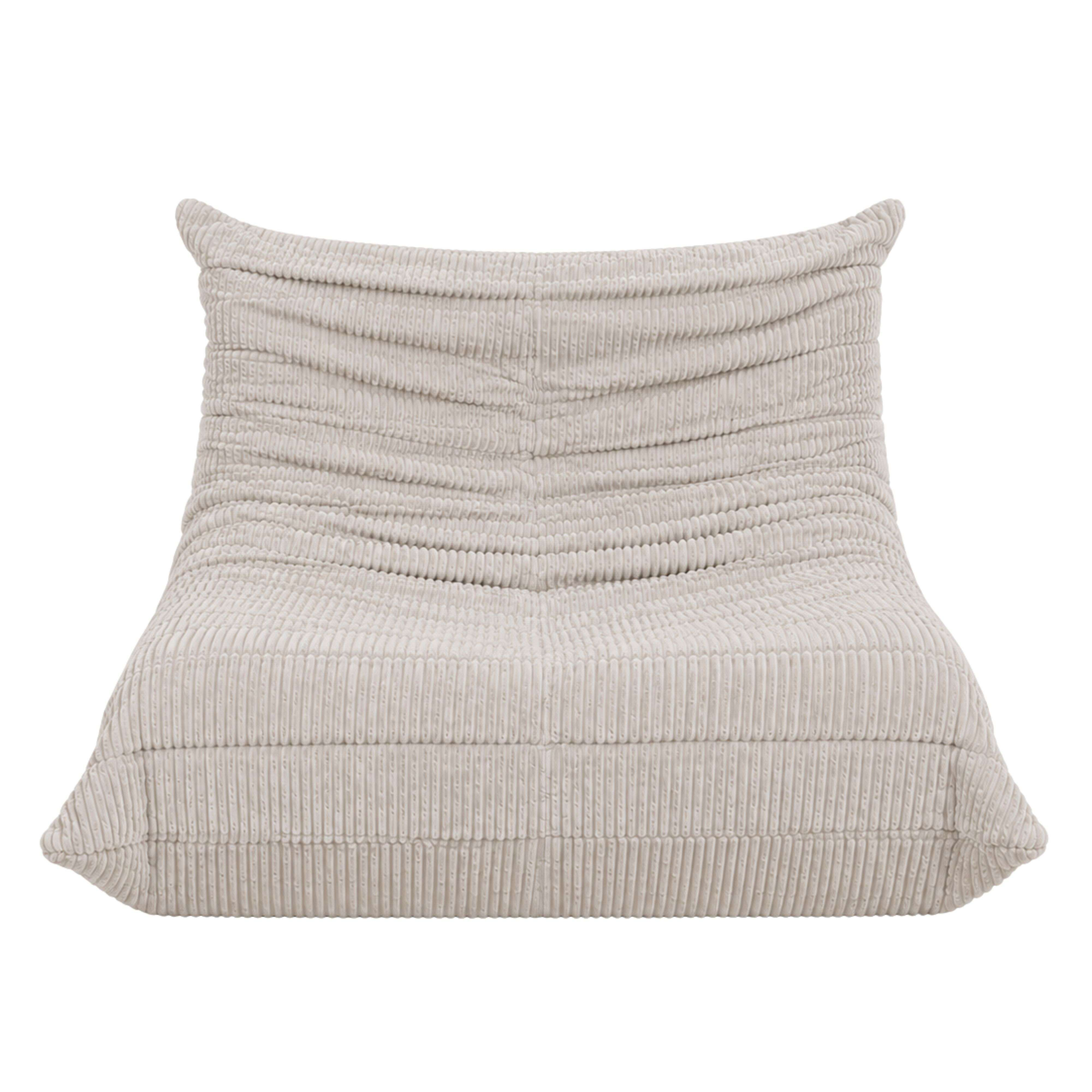 Un sillón de pana claro con pliegues en la tela.