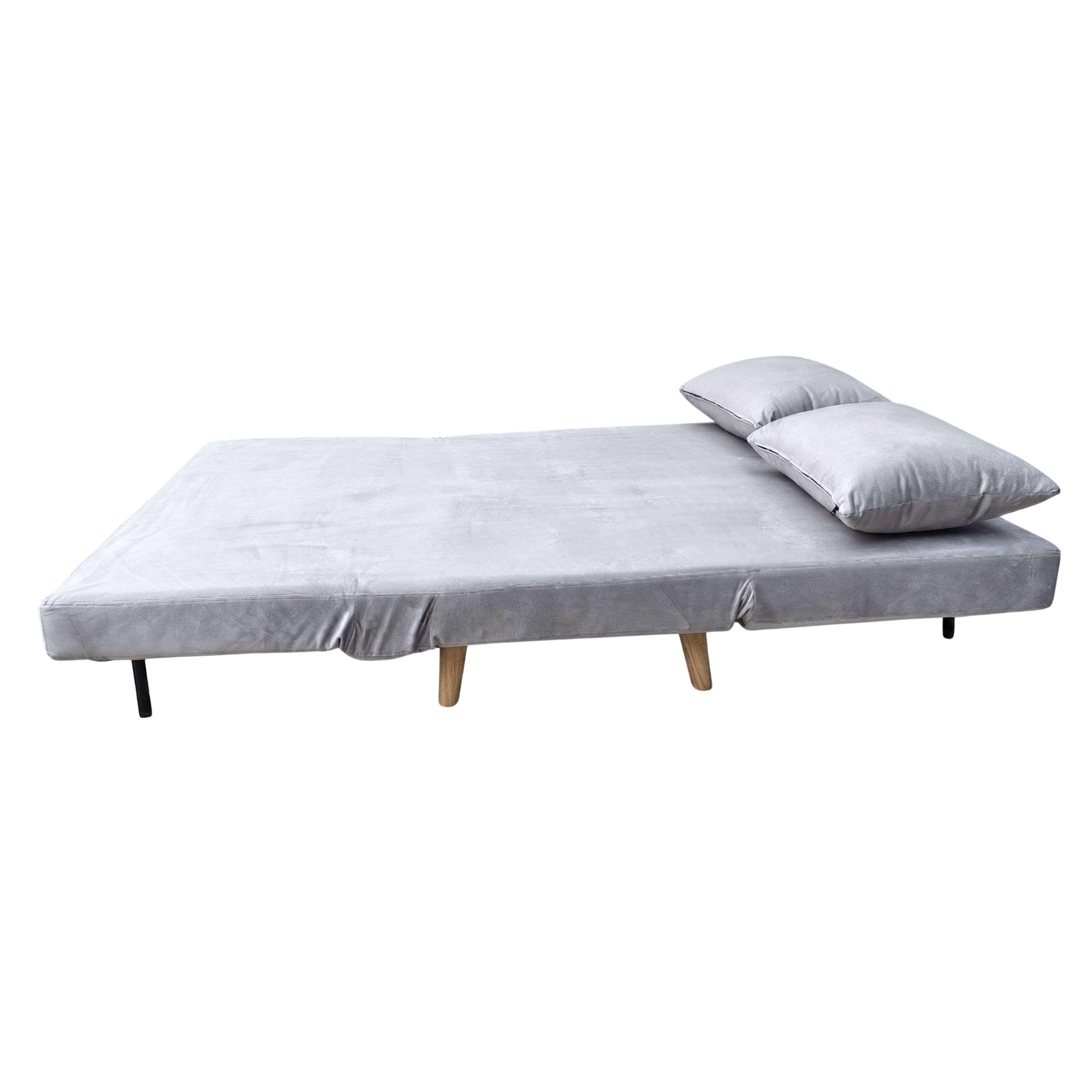 Un sofá cama gris con dos almohadas, sobre patas de madera blancas.