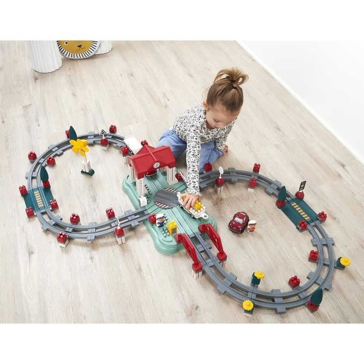 Una bambina gioca con un trenino giocattolo sul pavimento.
