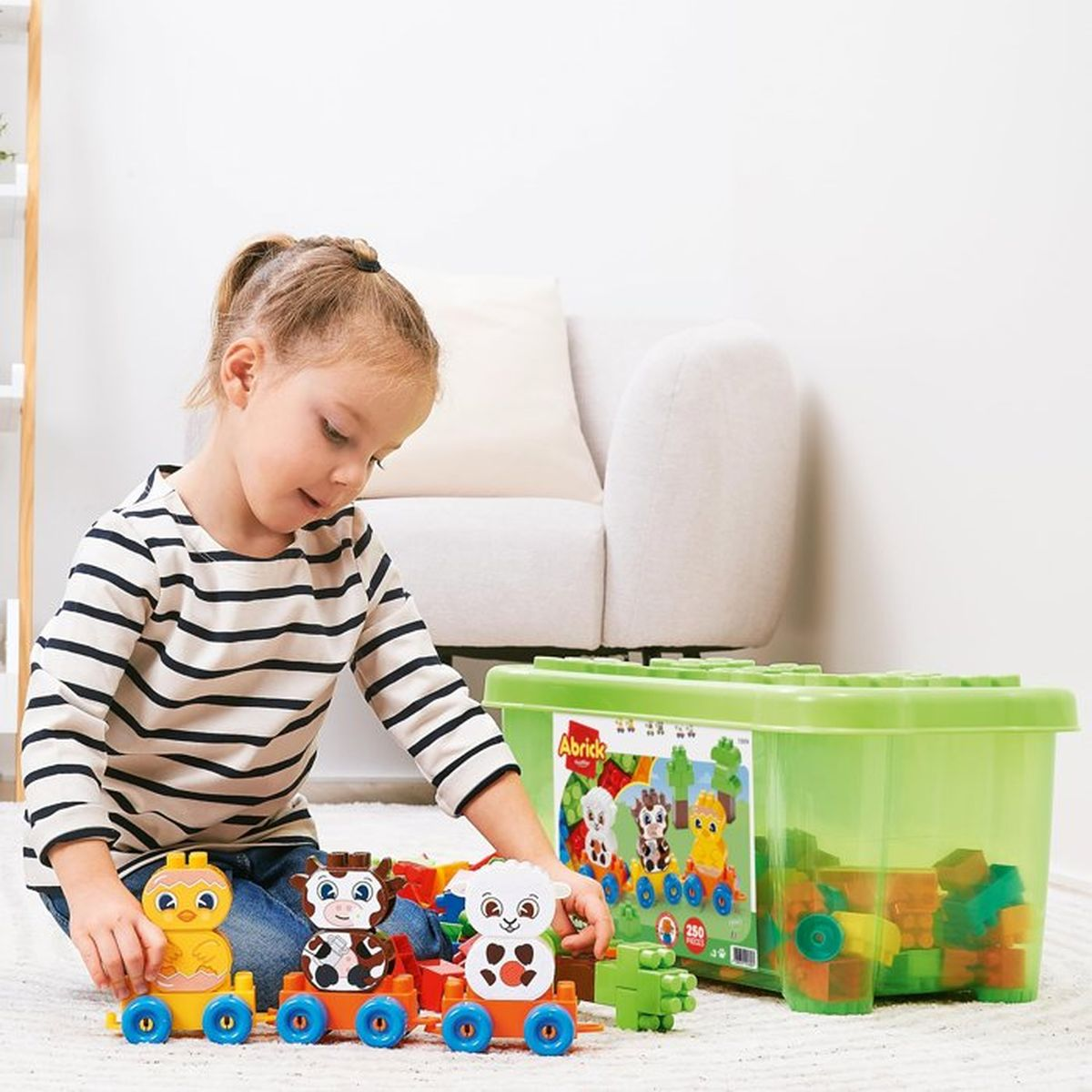 Una bambina gioca con un trenino di blocchi di animali accanto a una scatola.