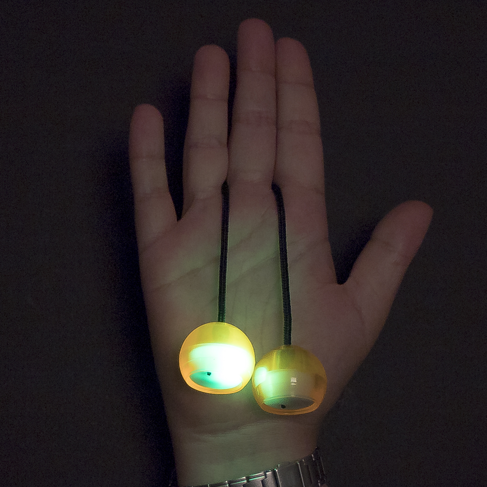 Palle gialle luminose su corde tenute su una mano al buio.