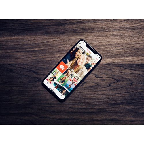 Smartfon z wieloma zdjęciami selfie leży na drewnianym stole.