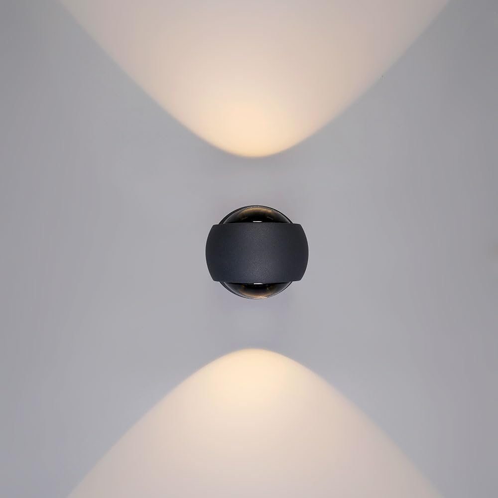 Eine dunkle, kugelförmige Wandleuchte mit nach oben und unten gerichteten Lichtkegeln.