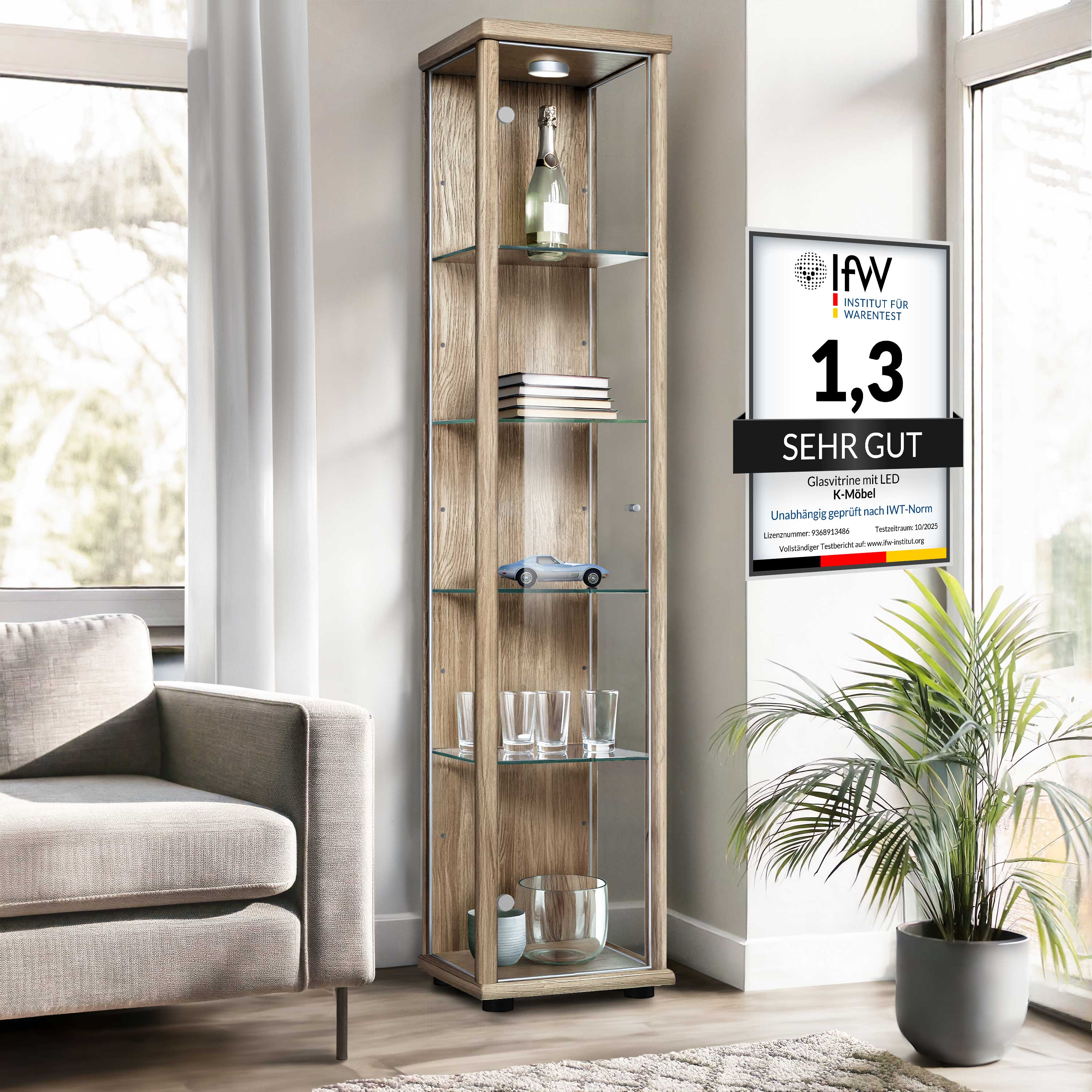 Eine Glasvitrine mit Holzoptik steht neben einem Sofa und einer Pflanze.