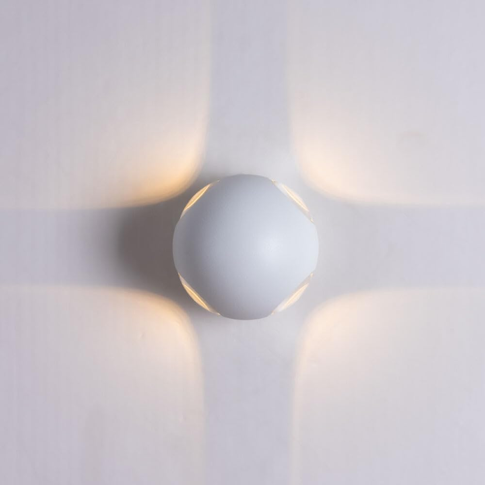 Eine weiße Kugelwandleuchte mit vier Lichtstrahlen auf weißem Hintergrund.