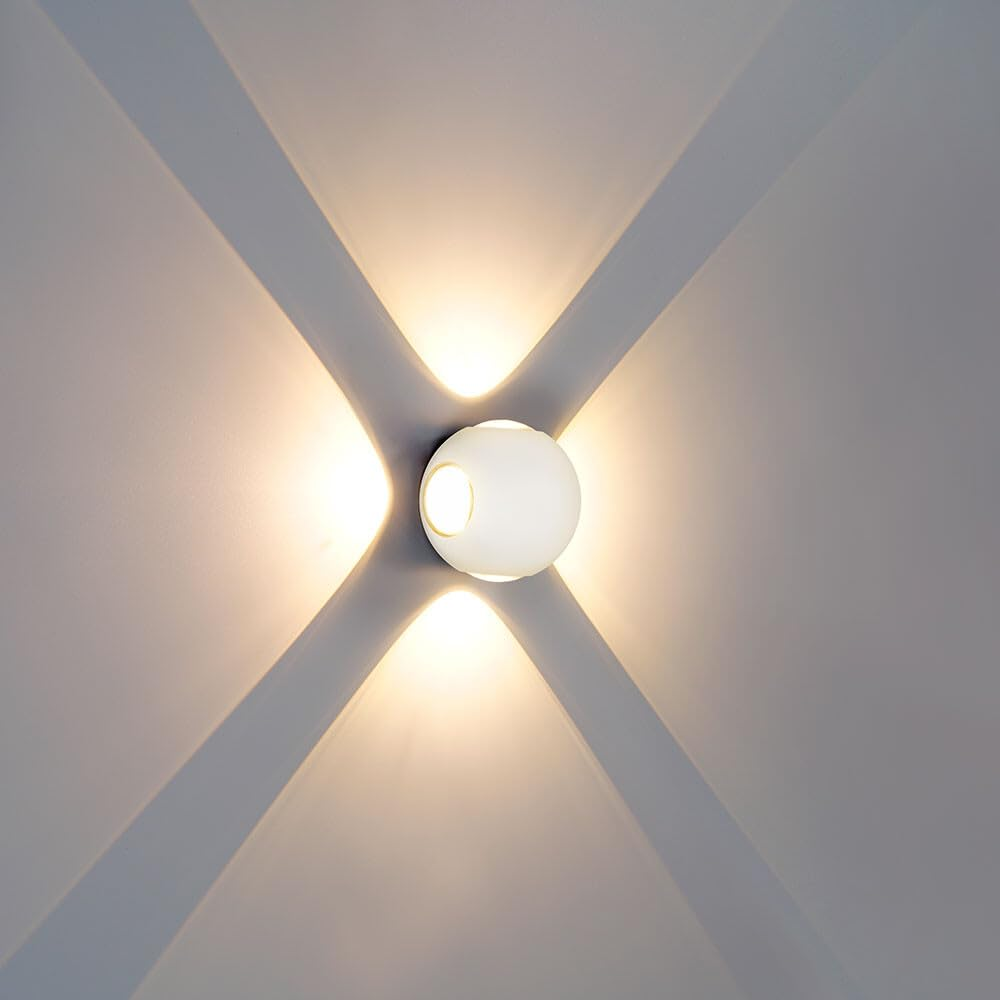 Eine weiße Kugelleuchte wirft vier Lichtkegel an eine graue Wand.
