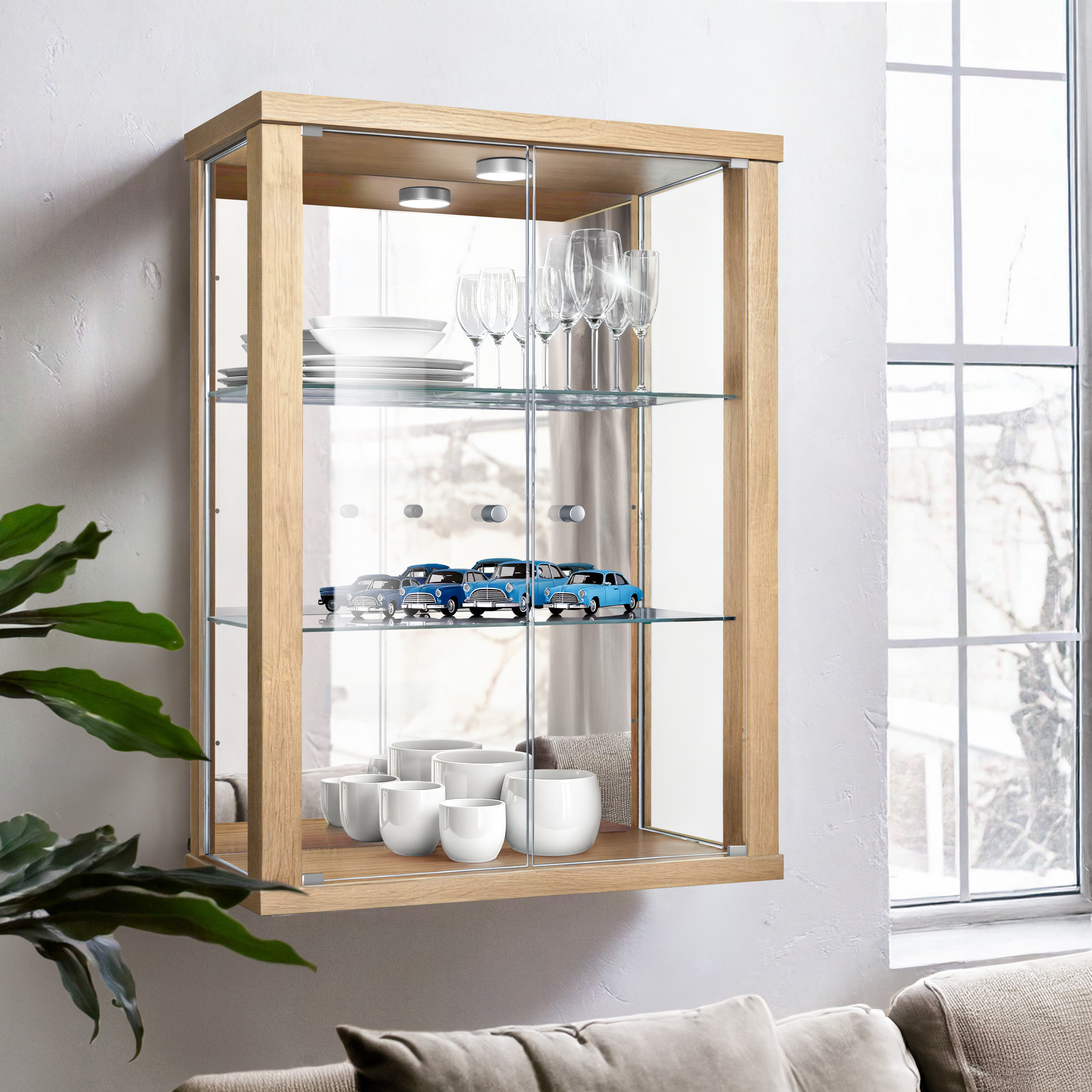 Ein hängender Holzschrank mit Glastüren, gefüllt mit Geschirr, Gläsern und Modellautos.