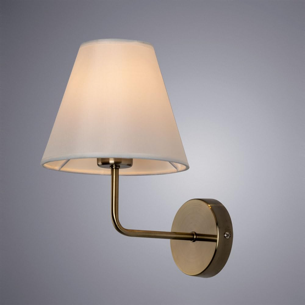 Eine Messing-Wandlampe mit weißem, konischem Schirm ist vor grauem Hintergrund beleuchtet.