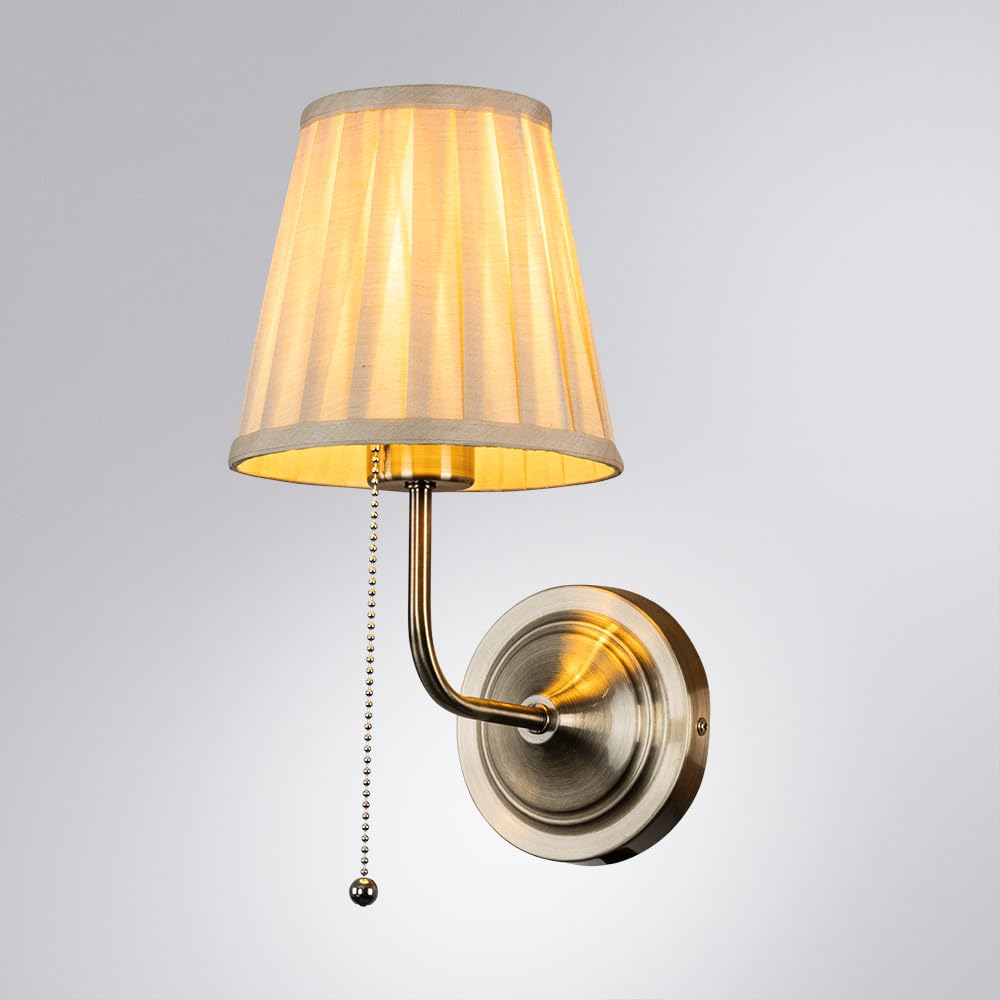 Eine Wandleuchte mit beige Faltenlampenschirm, Metallarm und Zugkette.