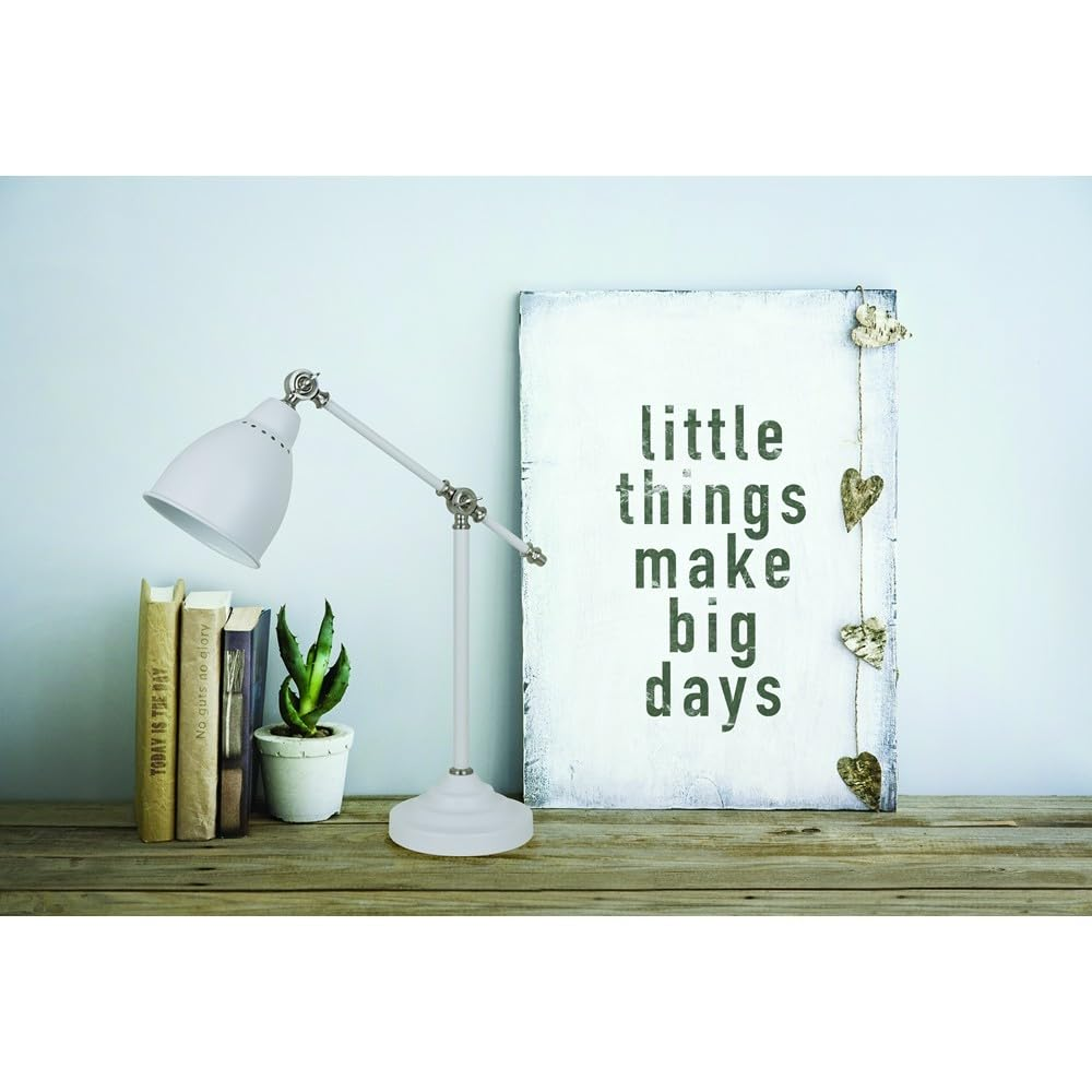 Eine weiße Schreibtischlampe steht neben Büchern und einer Pflanze, mit einem Schild 'little things make big days'.