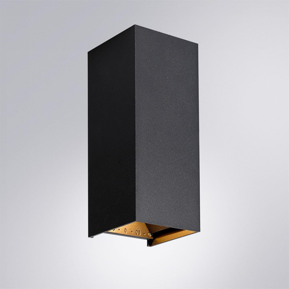 Schwarze rechteckige Wandleuchte mit goldenem Innenraum, auf grauem Hintergrund.