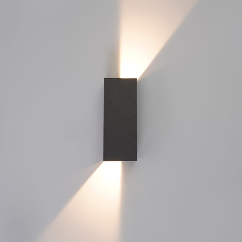 Eine dunkle rechteckige Wandleuchte wirft nach oben und unten Lichtstrahlen.