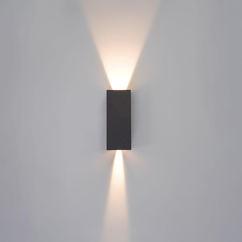 Ein dunkler, rechteckiger Wandleuchter wirft Licht nach oben und unten.