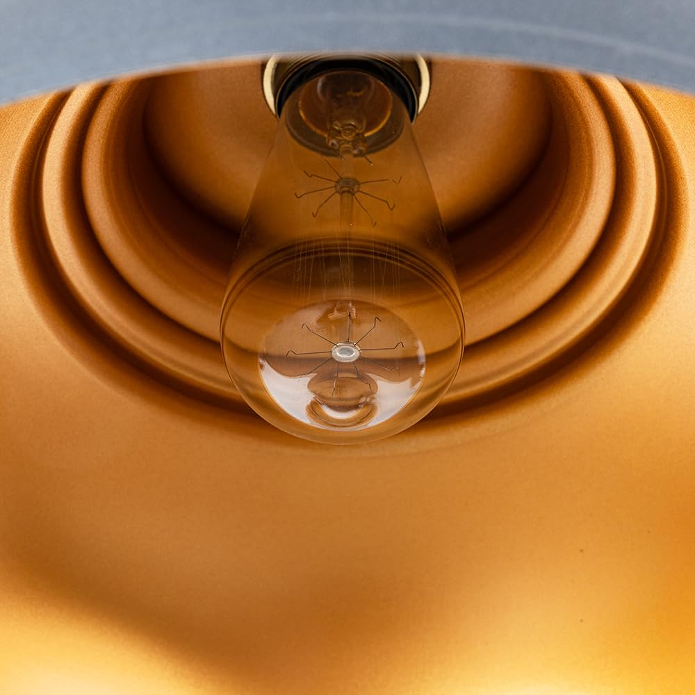 Nahaufnahme einer Glasglühbirne mit sichtbarem Glühfaden in einem goldenen Lampenschirm.