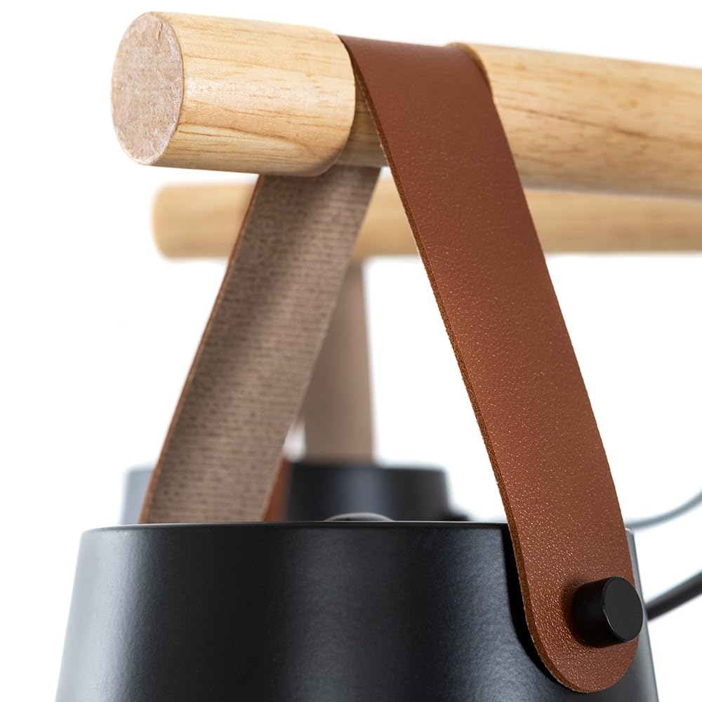 Nahaufnahme einer schwarzen Lampe mit Holzgriff und braunen Lederriemen.
