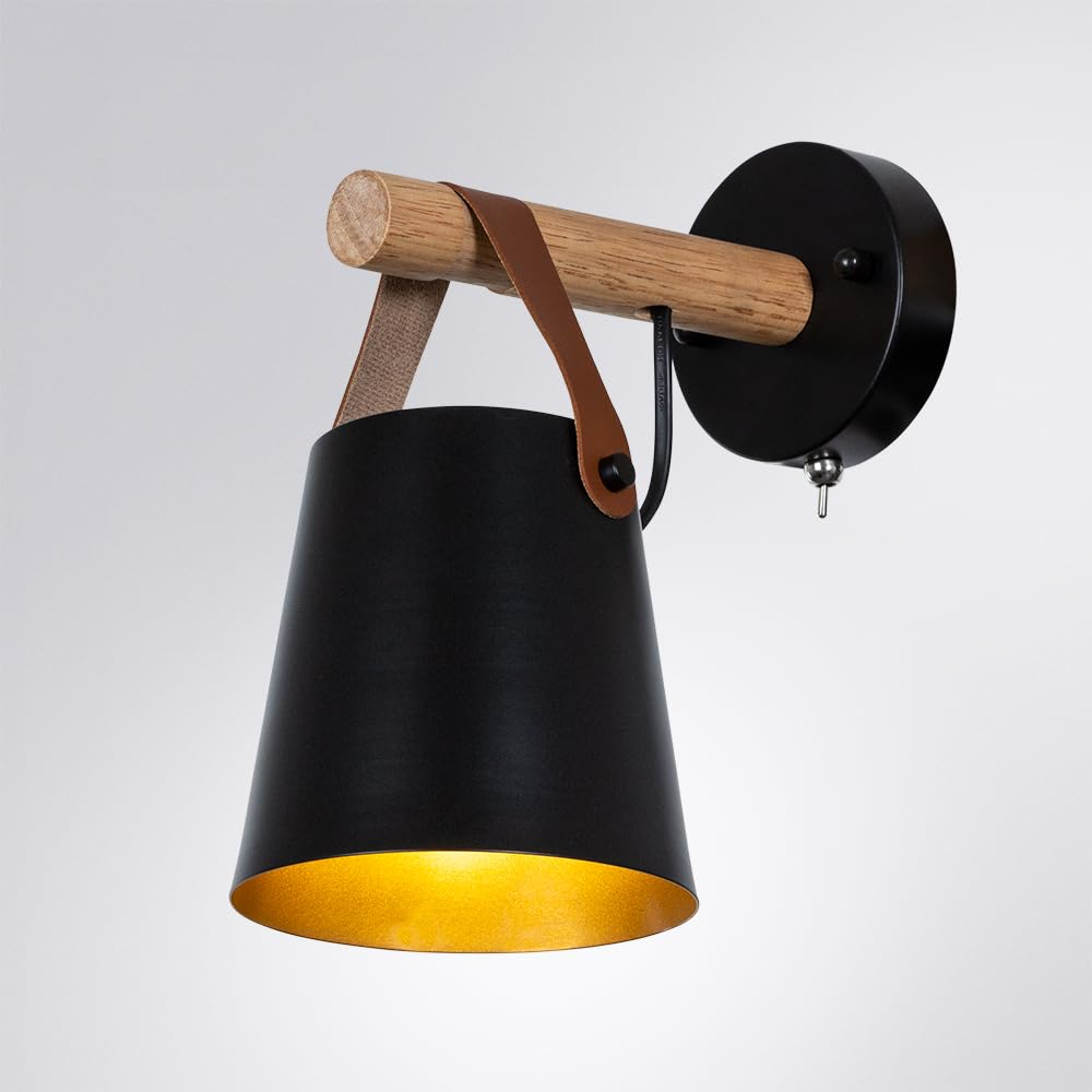 Eine schwarze Wandleuchte mit Holzarm und Lederschlaufe, goldfarben beleuchtet.