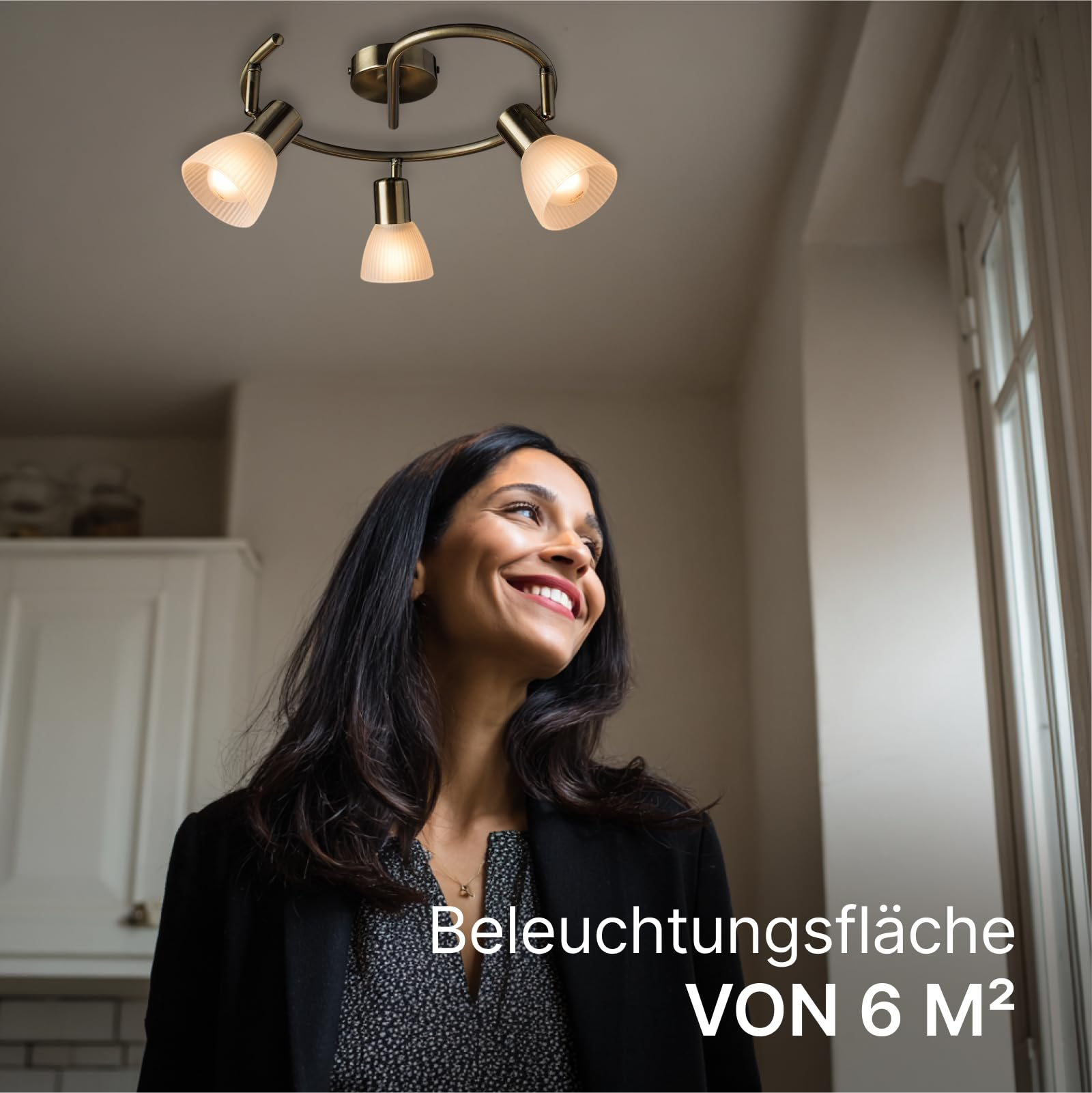 Eine Frau blickt lächelnd nach oben, beleuchtet von einer Deckenleuchte.
