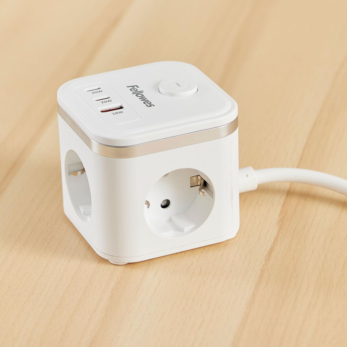 Ein weißer Würfel-Steckdosenadapter mit USB-Anschlüssen und Steckdosen auf Holztisch.