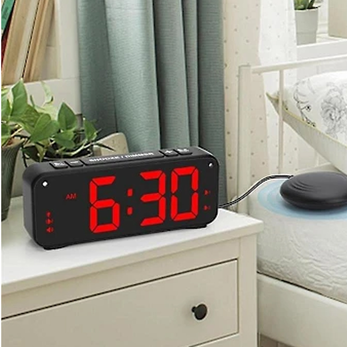 Digitaler Wecker zeigt 6:30 AM, neben einem Bett mit Vibrationsalarm.