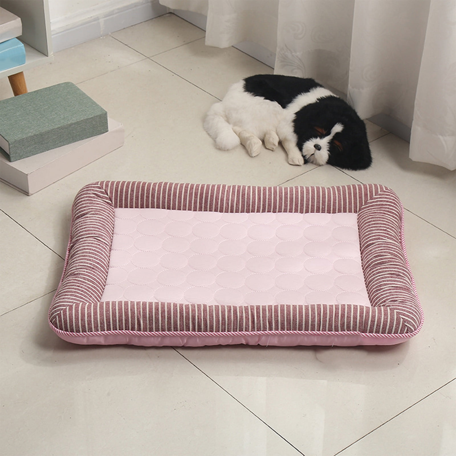 Ein gestreiftes Hundebett mit rosa Einlage liegt auf dem Boden. Ein Spielzeughund schläft daneben.