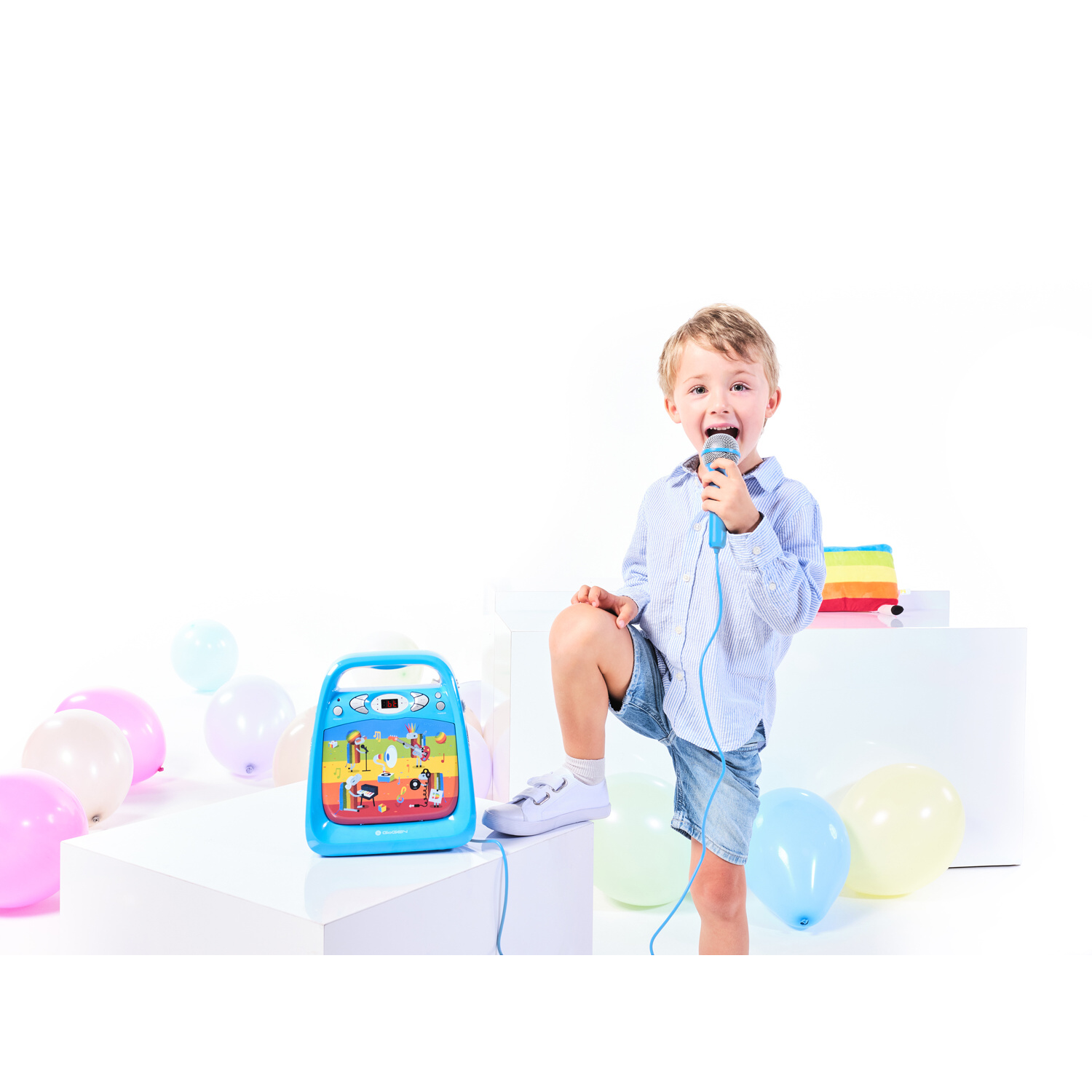Un bambino tiene un microfono accanto a un dispositivo blu con immagini colorate e palloncini.