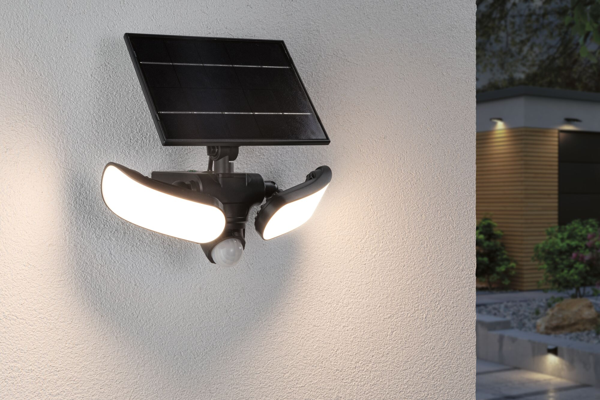 Zewnętrzna lampa solarna z dwoma kloszami i czujnikiem ruchu na ścianie.