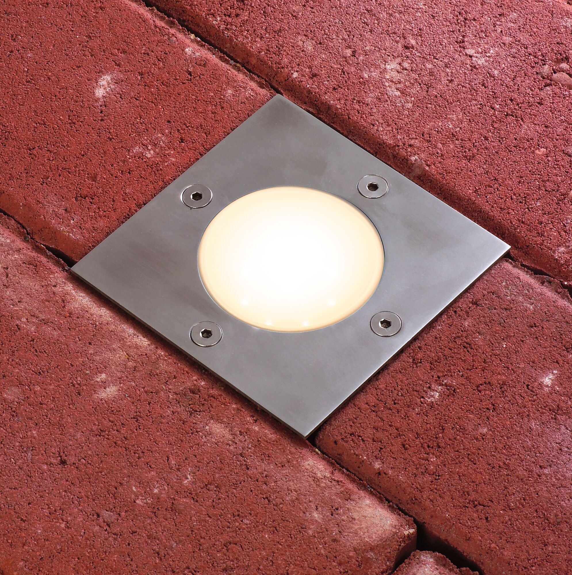 Una luce quadrata incassata con illuminazione brillante su pavimentazione rossa.