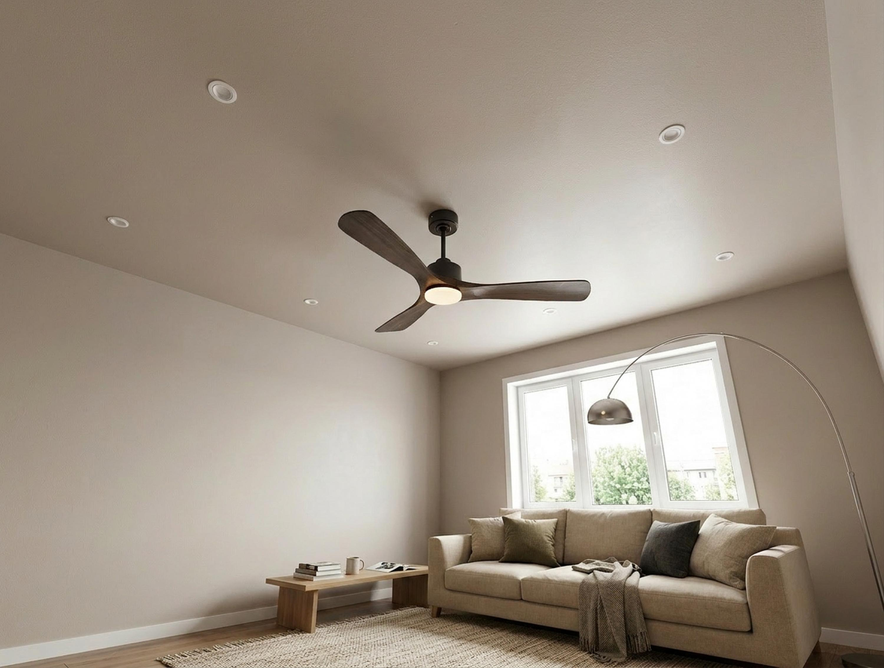 Una sala de estar con sofá, mesa de centro, ventilador de techo y ventana.