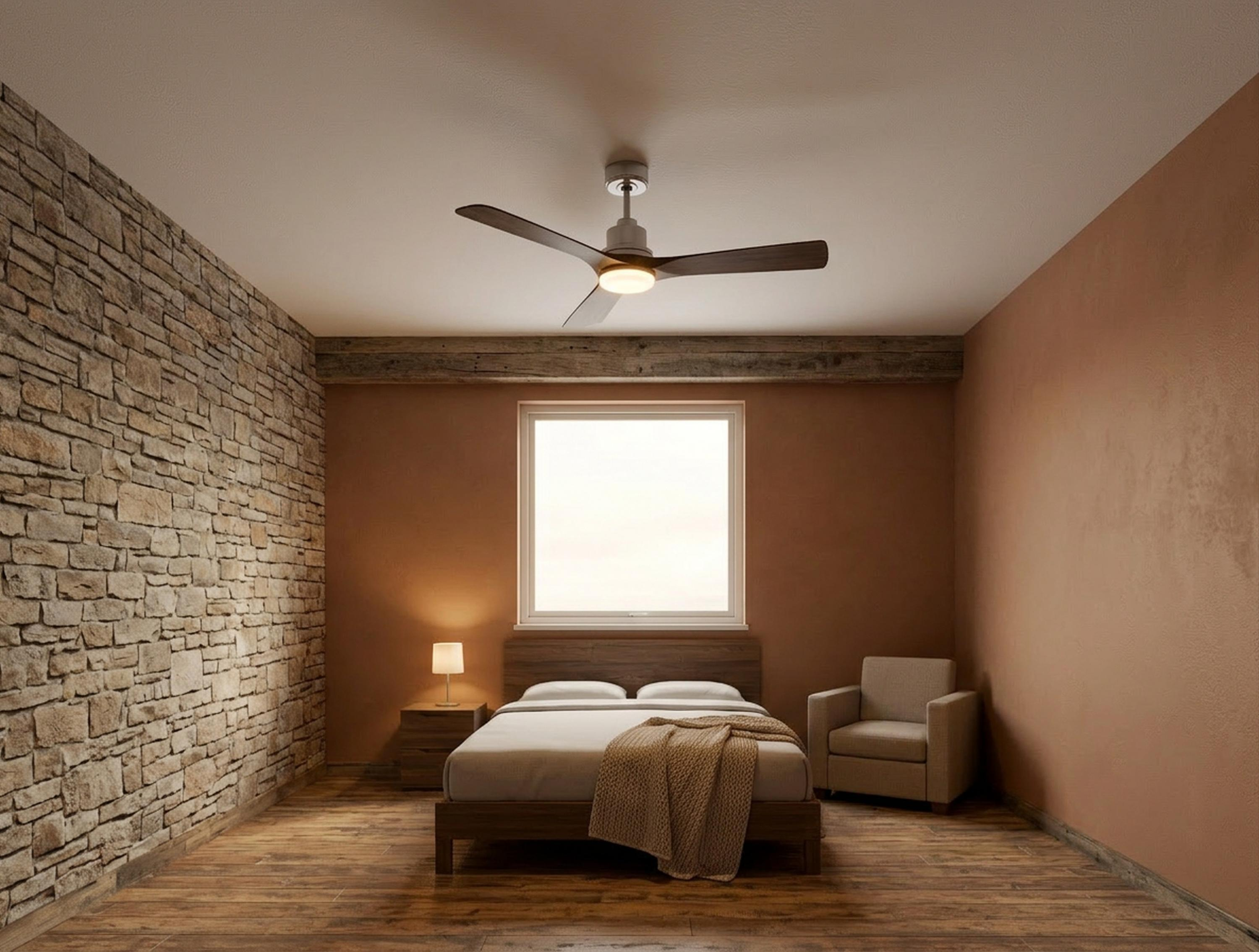 Un dormitorio con pared de piedra, cama, sillón y ventilador de techo.