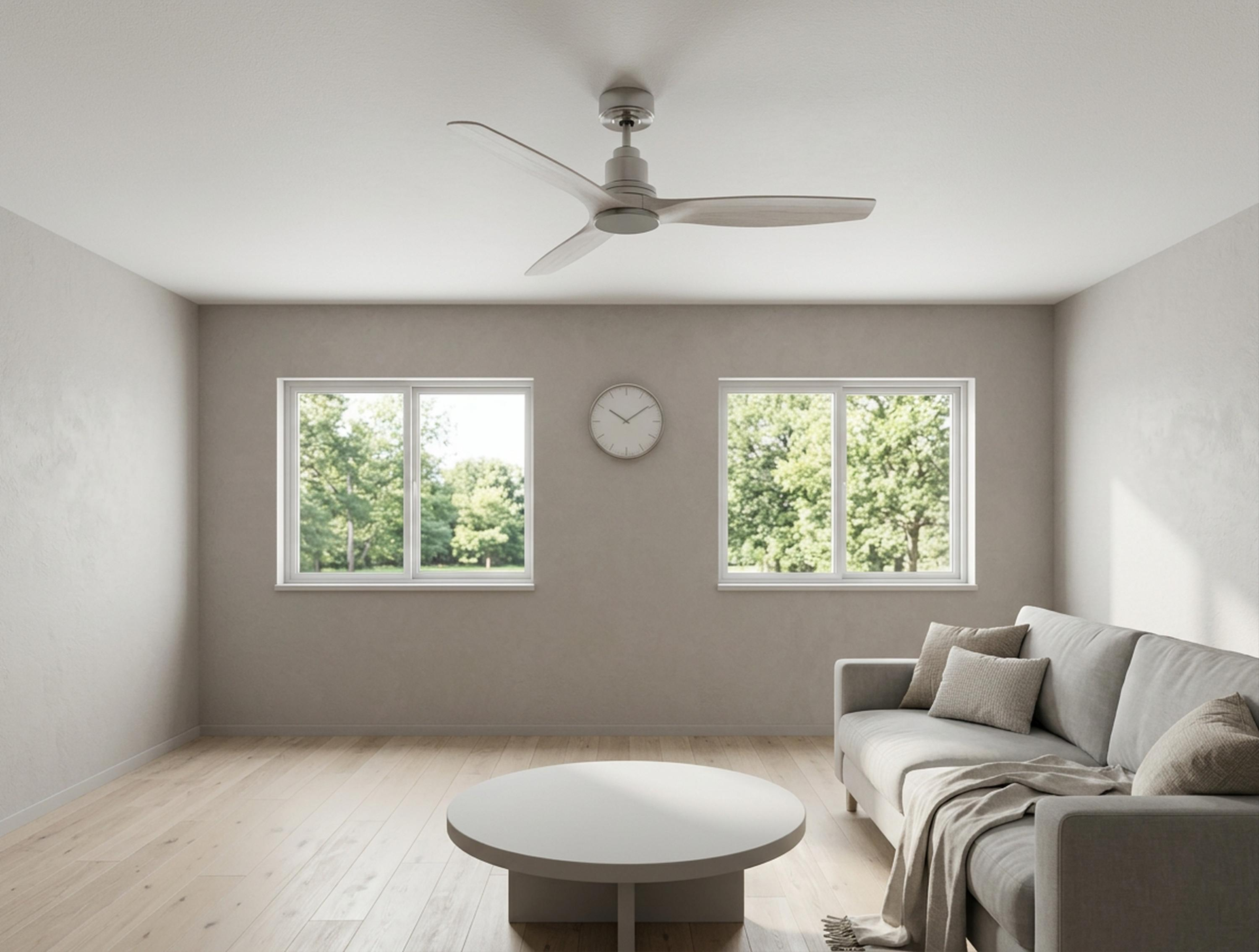 Una sala de estar luminosa con sofá, mesa de centro, ventilador de techo y dos ventanas con vistas a árboles.