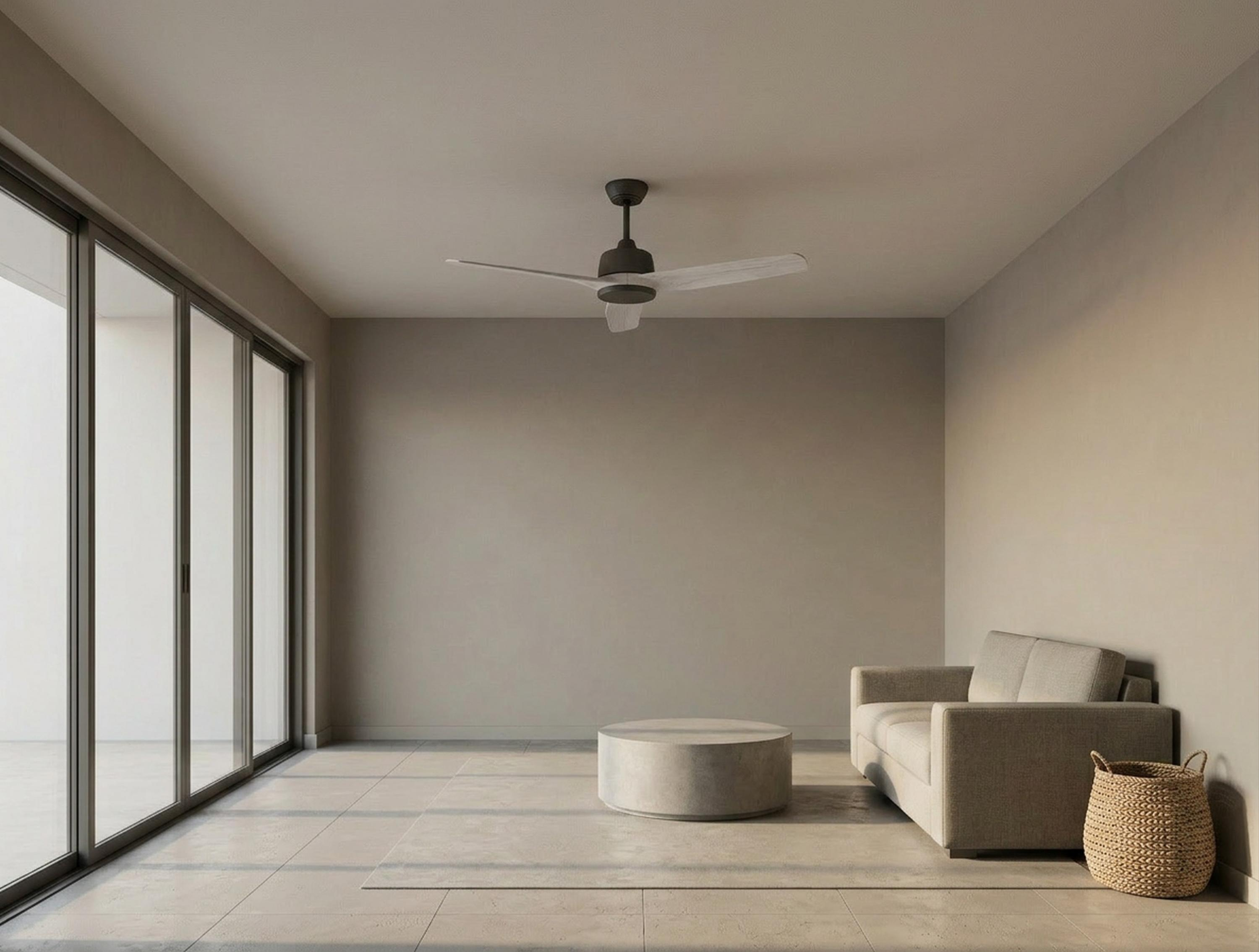 Una sala de estar con sofá, mesa de centro, ventilador de techo y grandes ventanales.