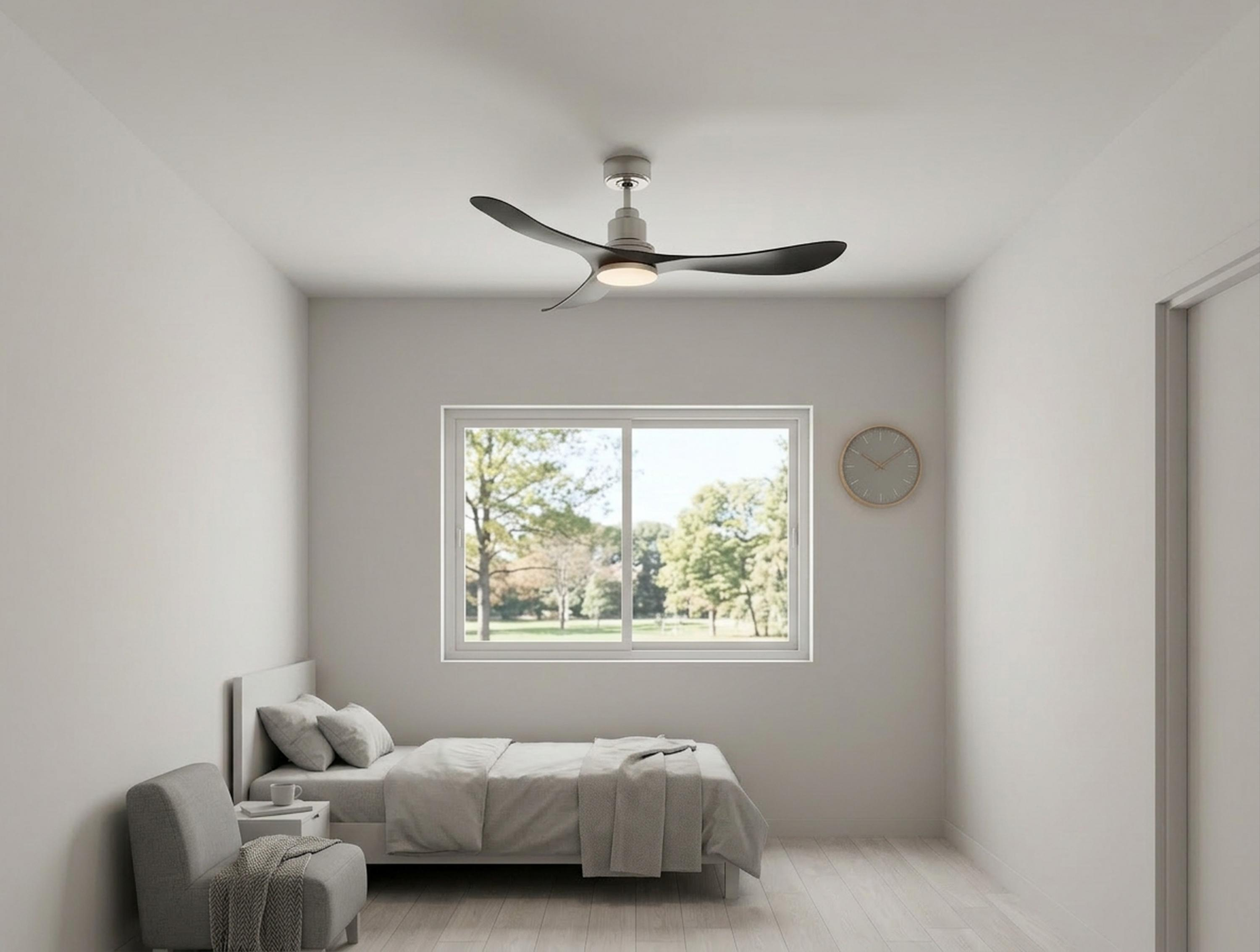 Un dormitorio con cama, sillón, ventilador de techo y ventana con vista a árboles.