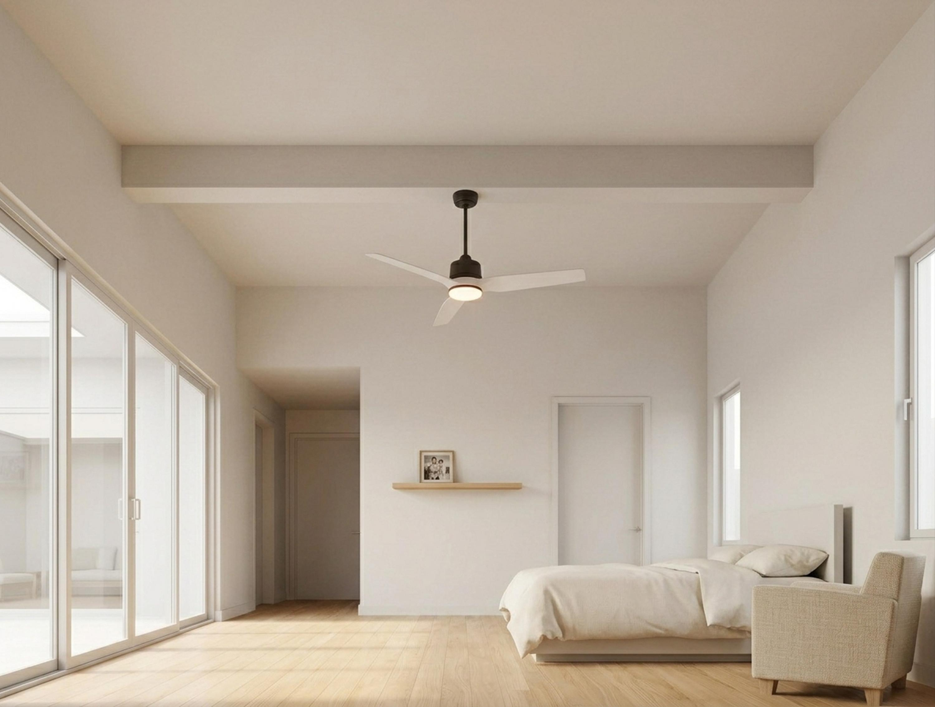 Un dormitorio con cama, sillón, ventilador de techo y grandes ventanales.