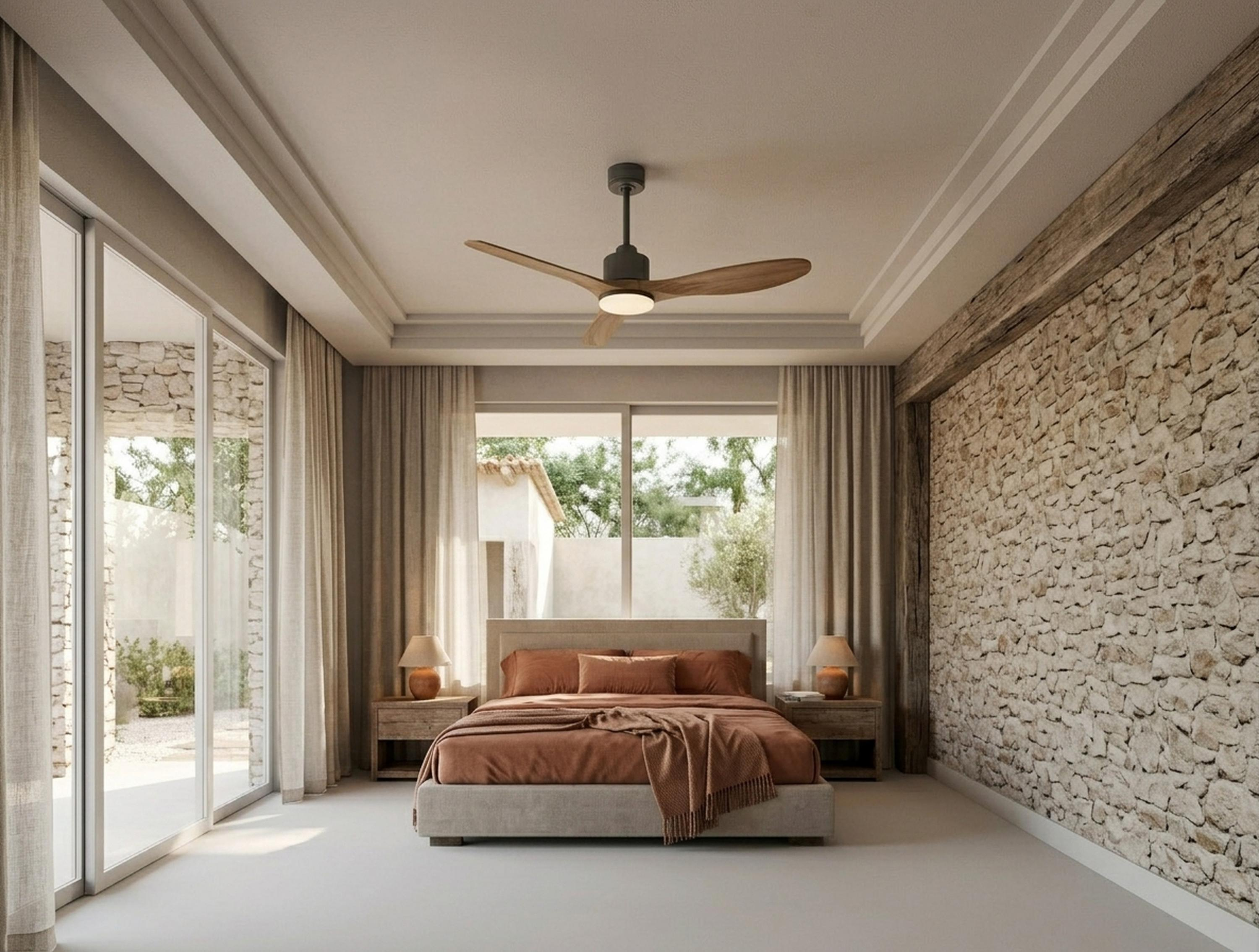 Un dormitorio con paredes de piedra, una cama y un ventilador de techo.