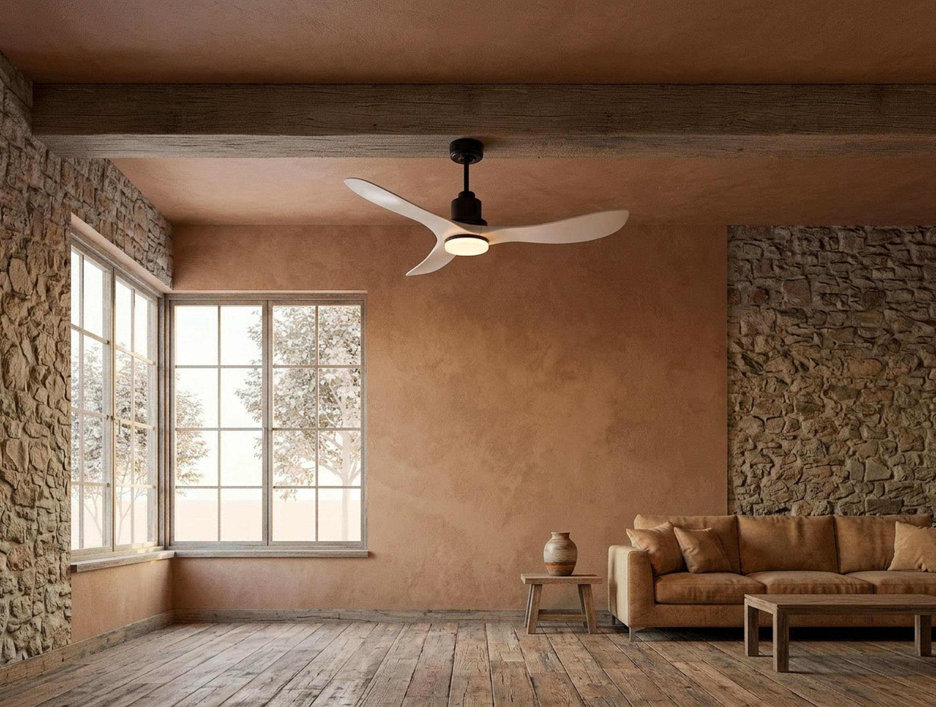 Una sala de estar con paredes de piedra, suelo de madera, sofá, mesa y ventilador de techo.