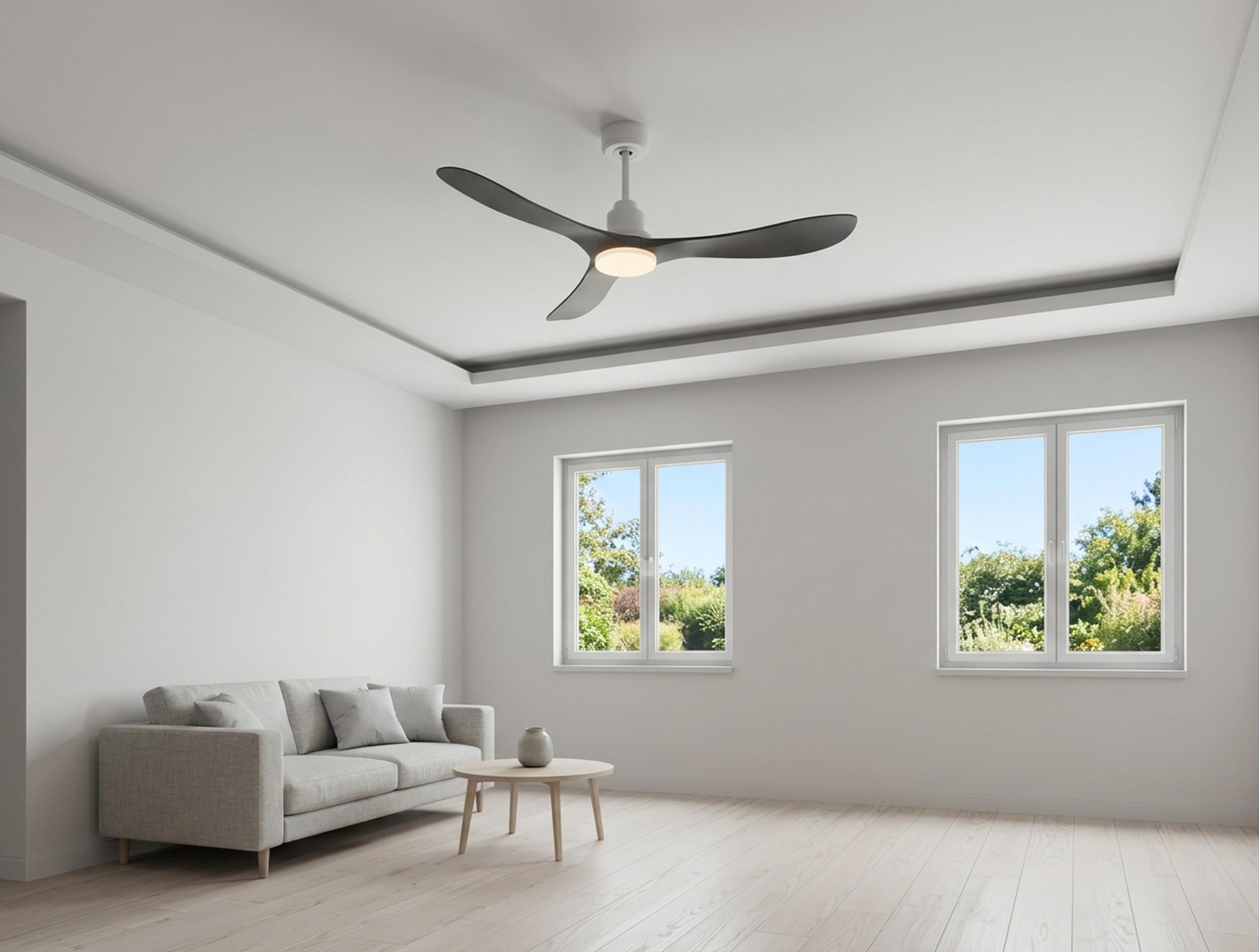 Ein helles Wohnzimmer mit Sofa, Couchtisch, Deckenventilator und Fenstern mit Blick ins Grüne.